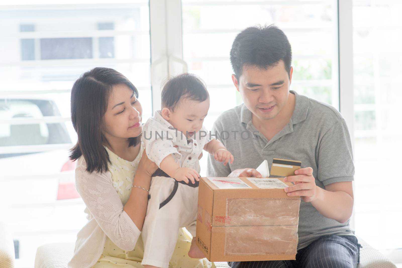 Online shopping with credit card. Happy Asian family at home, natural living lifestyle indoors.