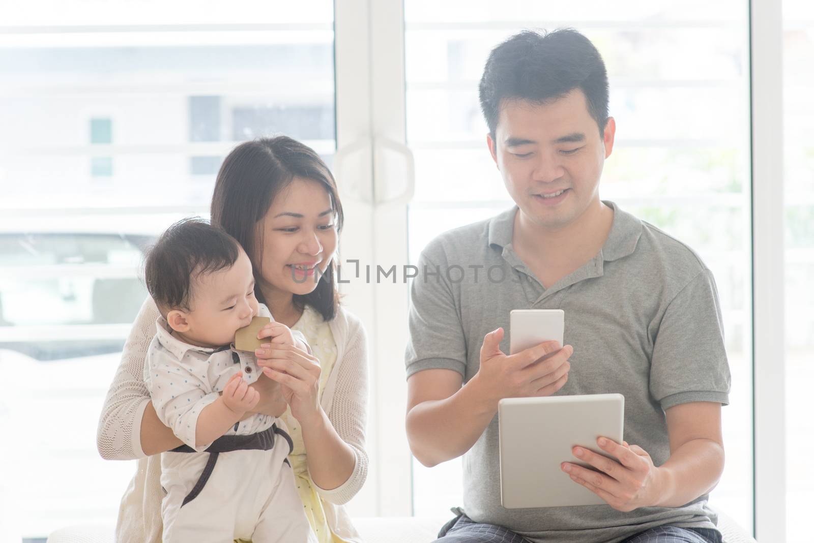 Chinese man scanning QR code with smart phone. Asian family at home, natural living lifestyle indoors.