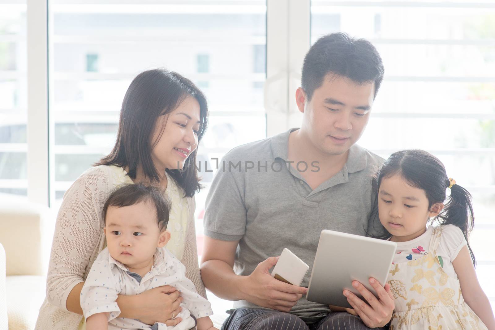 Father using tablet pc and smart phone. Asian family at home, natural living lifestyle indoors.