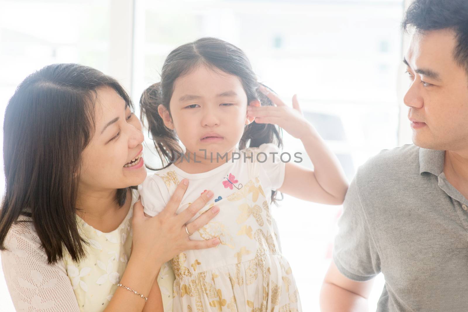 Parents comforting crying child at home by szefei