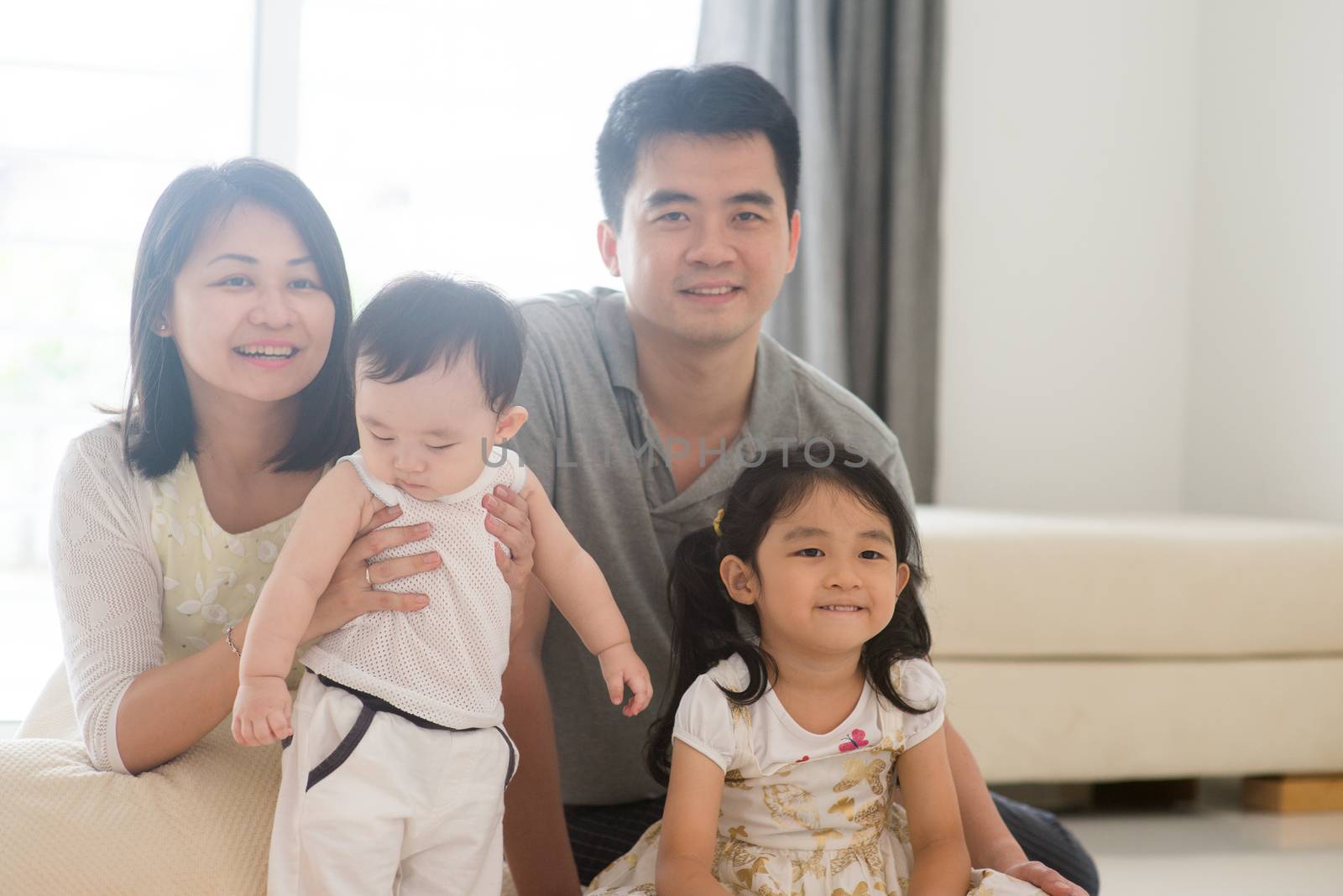 Parents and children sitting on floor. Happy Asian family spending quality time at home, natural living lifestyle indoors.