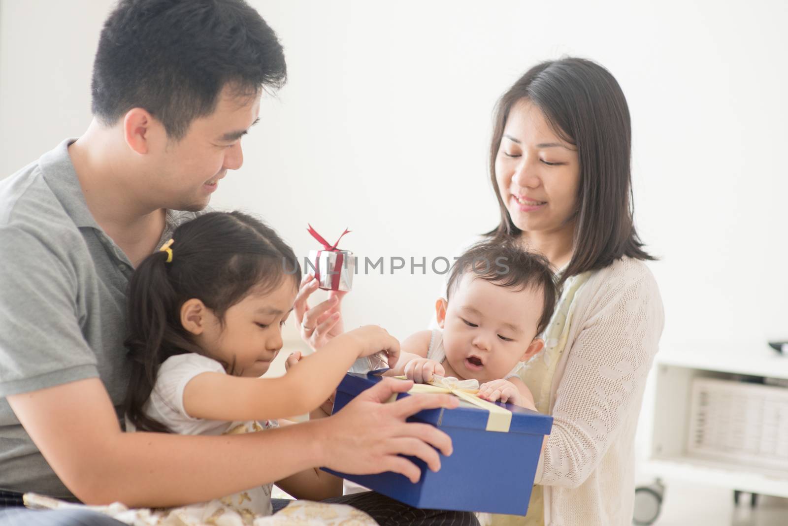 Parents and children boxing together. Asian family spending quality time at home, natural living lifestyle indoors.