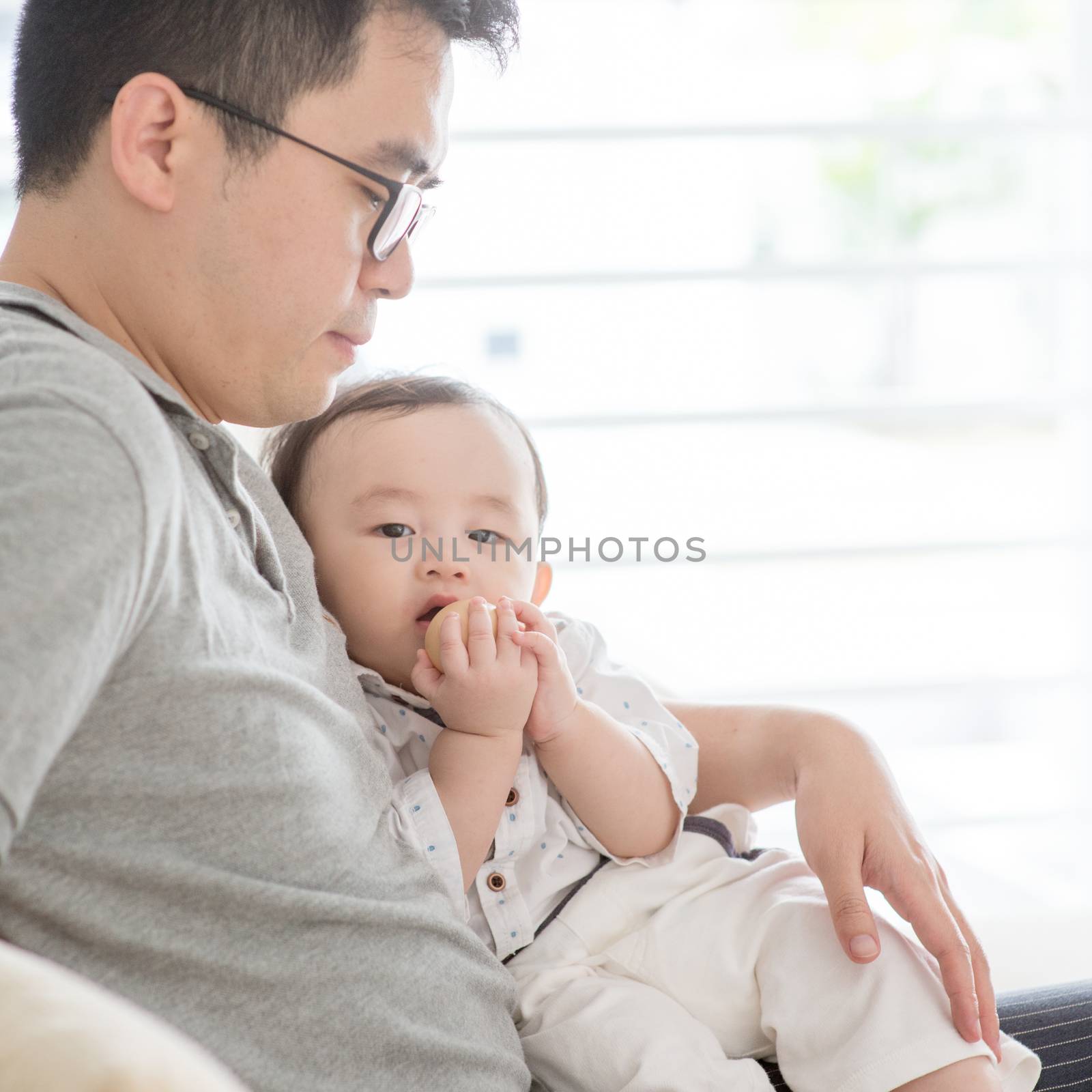 Asian family at home. Father holding baby boy, living lifestyle indoors. 