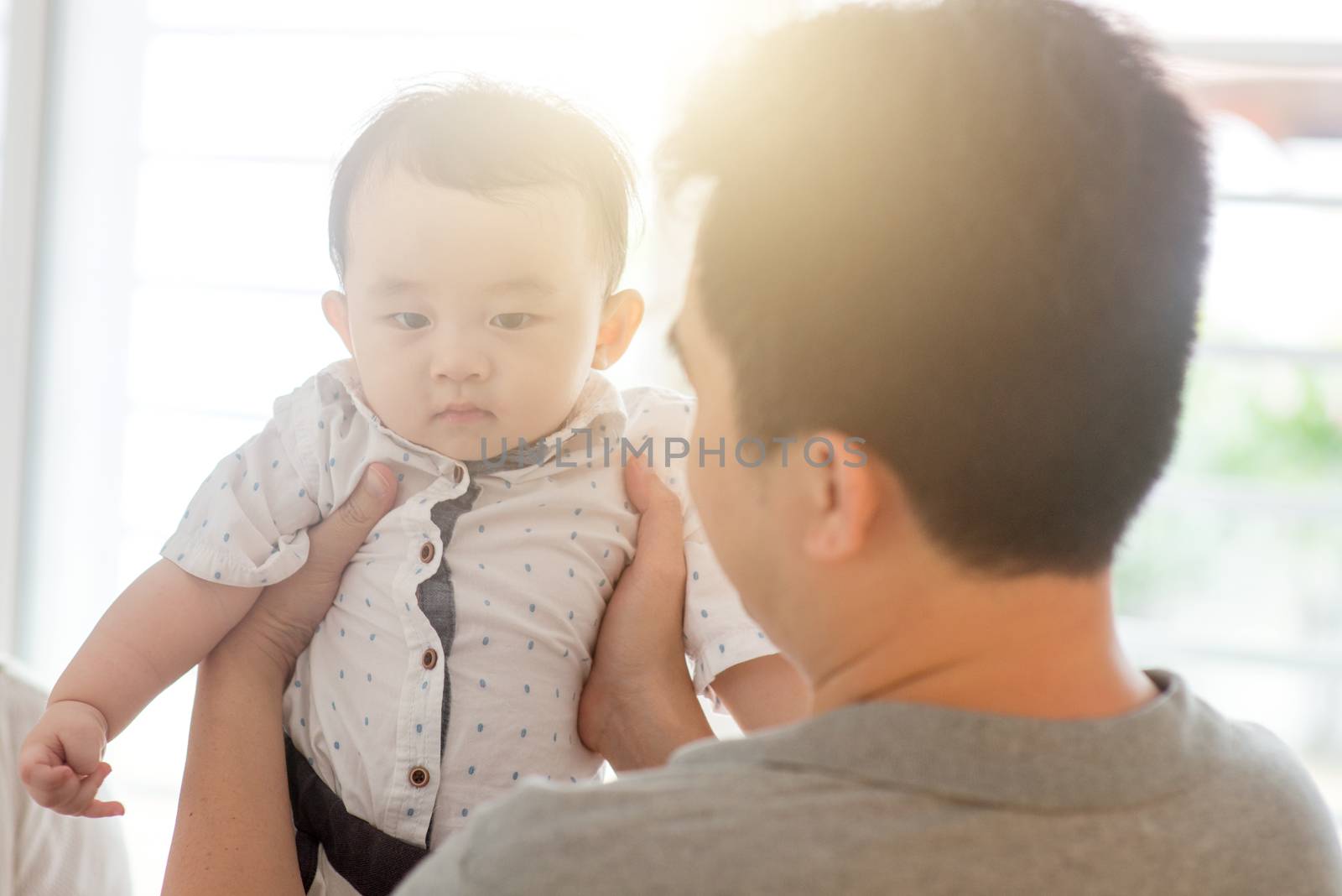 Asian family at home. Father holding child, living lifestyle indoors. 