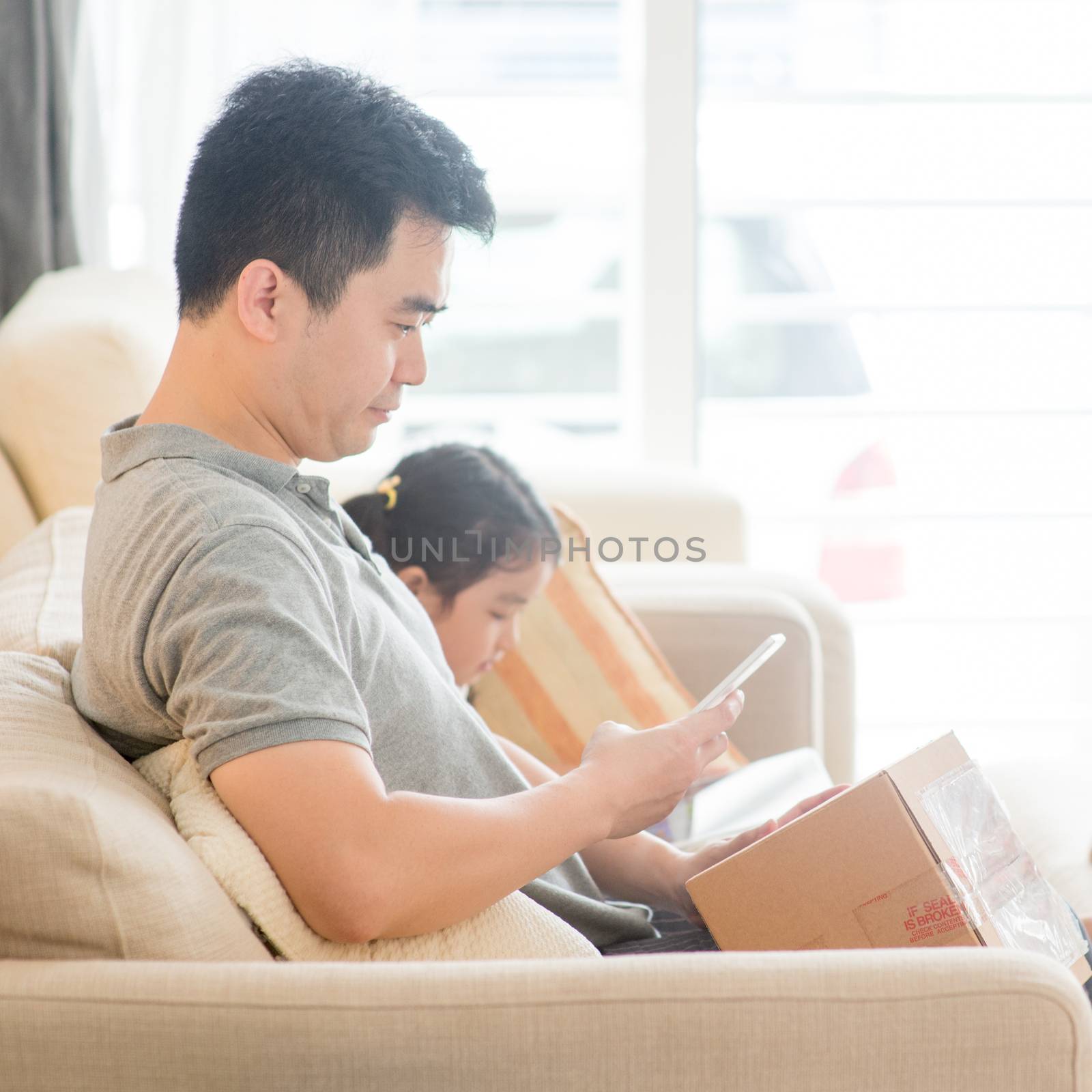 Man scanning QR code with smart phone. Asian family at home, living lifestyle indoors.