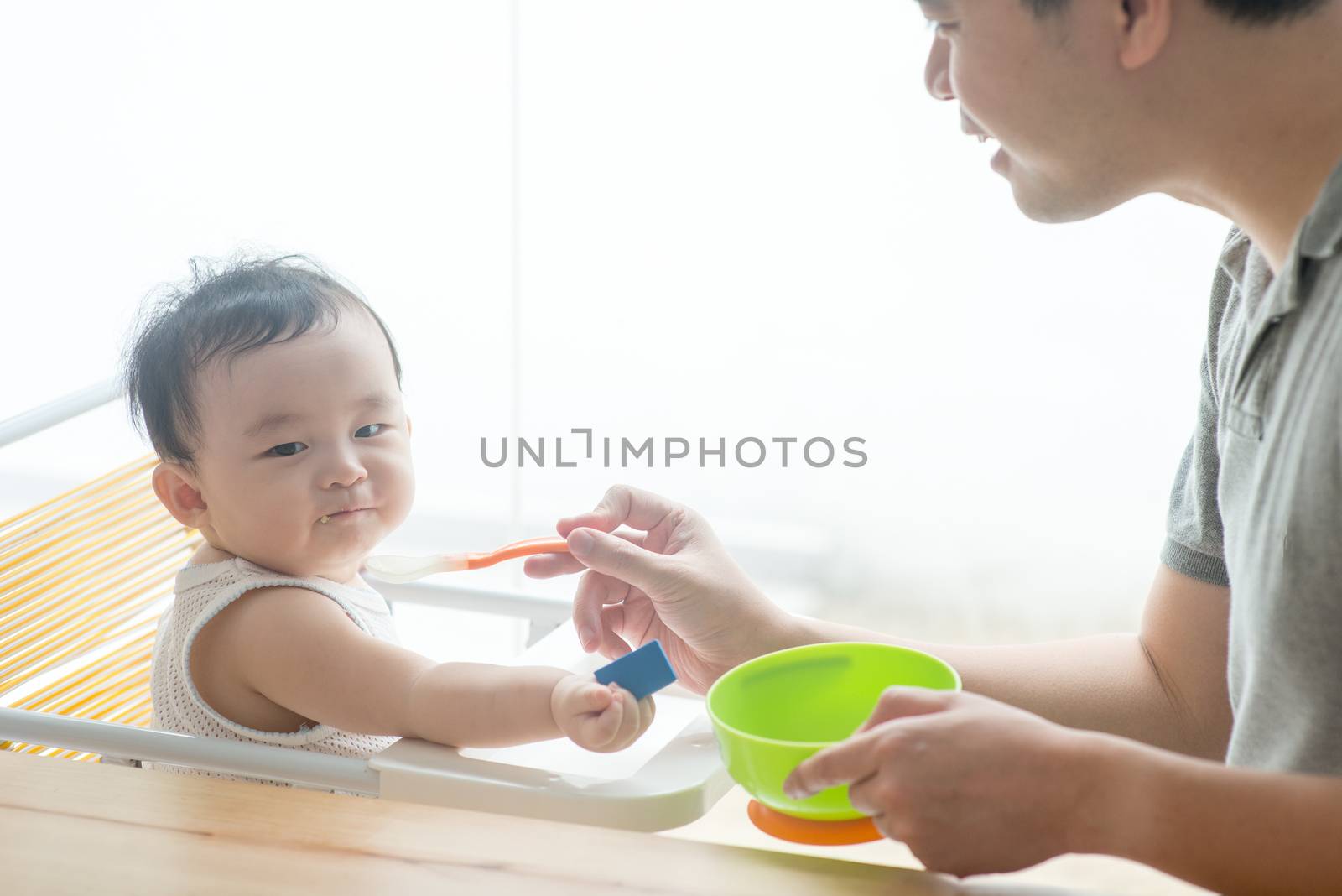 Father feeding toddler solid food. by szefei
