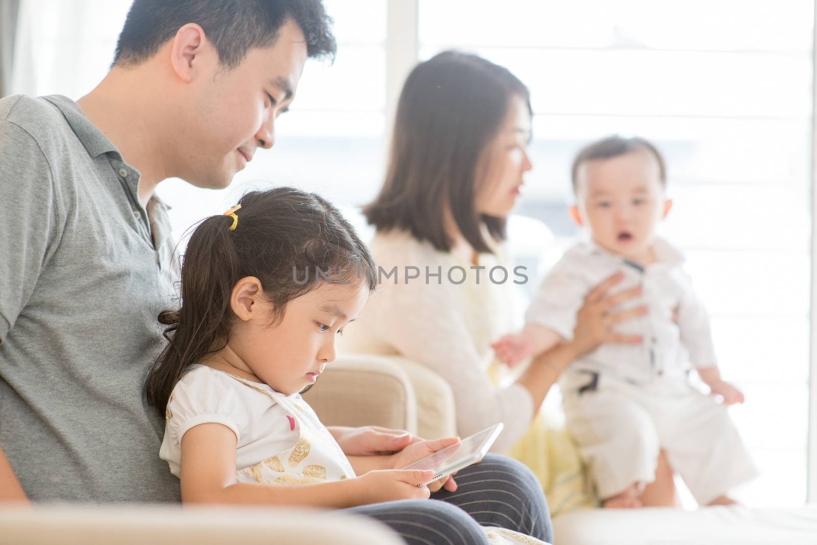 Happy Asian family at home, father and daughter playing tablet pc, natural living lifestyle indoors.