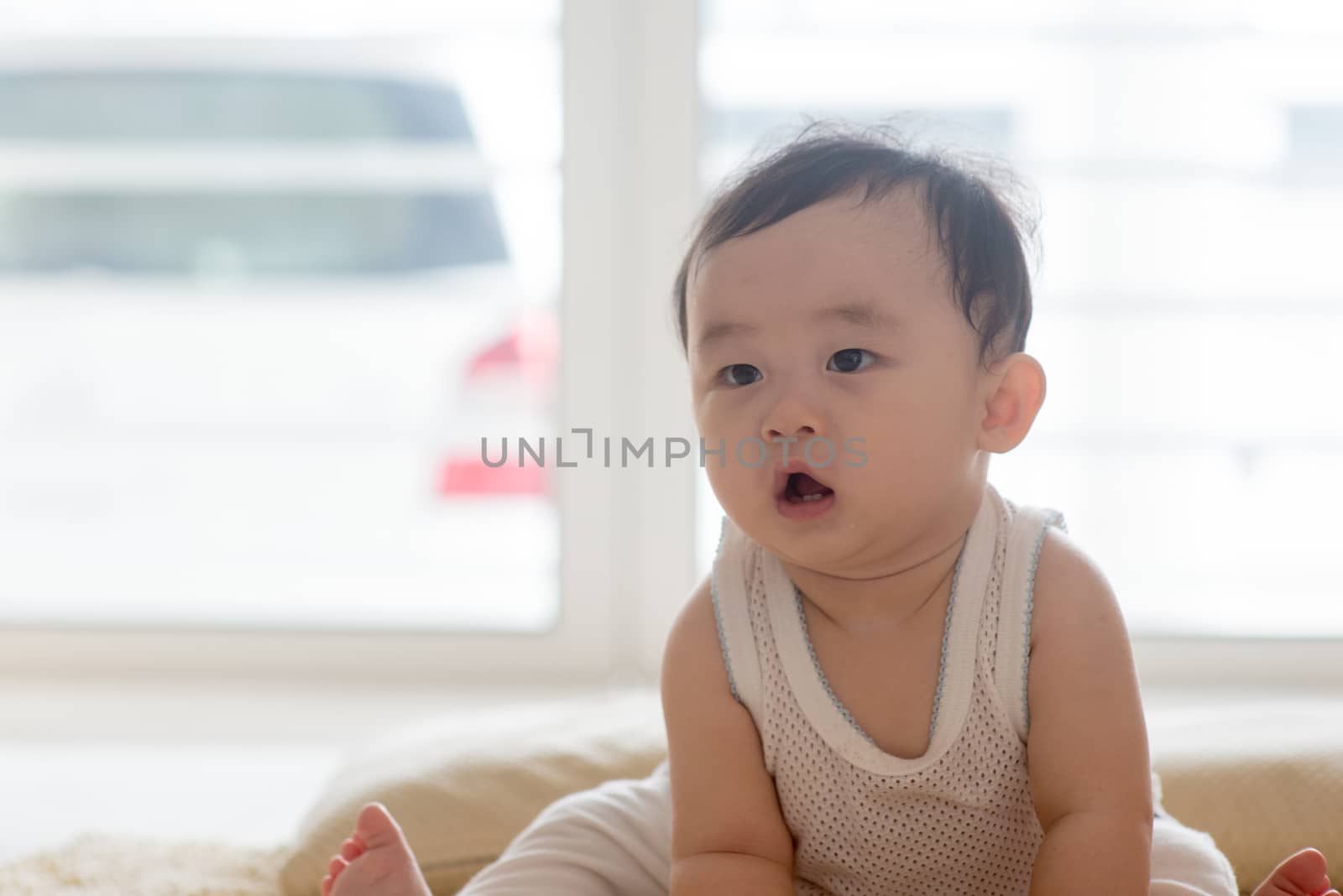 Nine months old baby boy sitting on floor. Asian family at home, living lifestyle indoors.