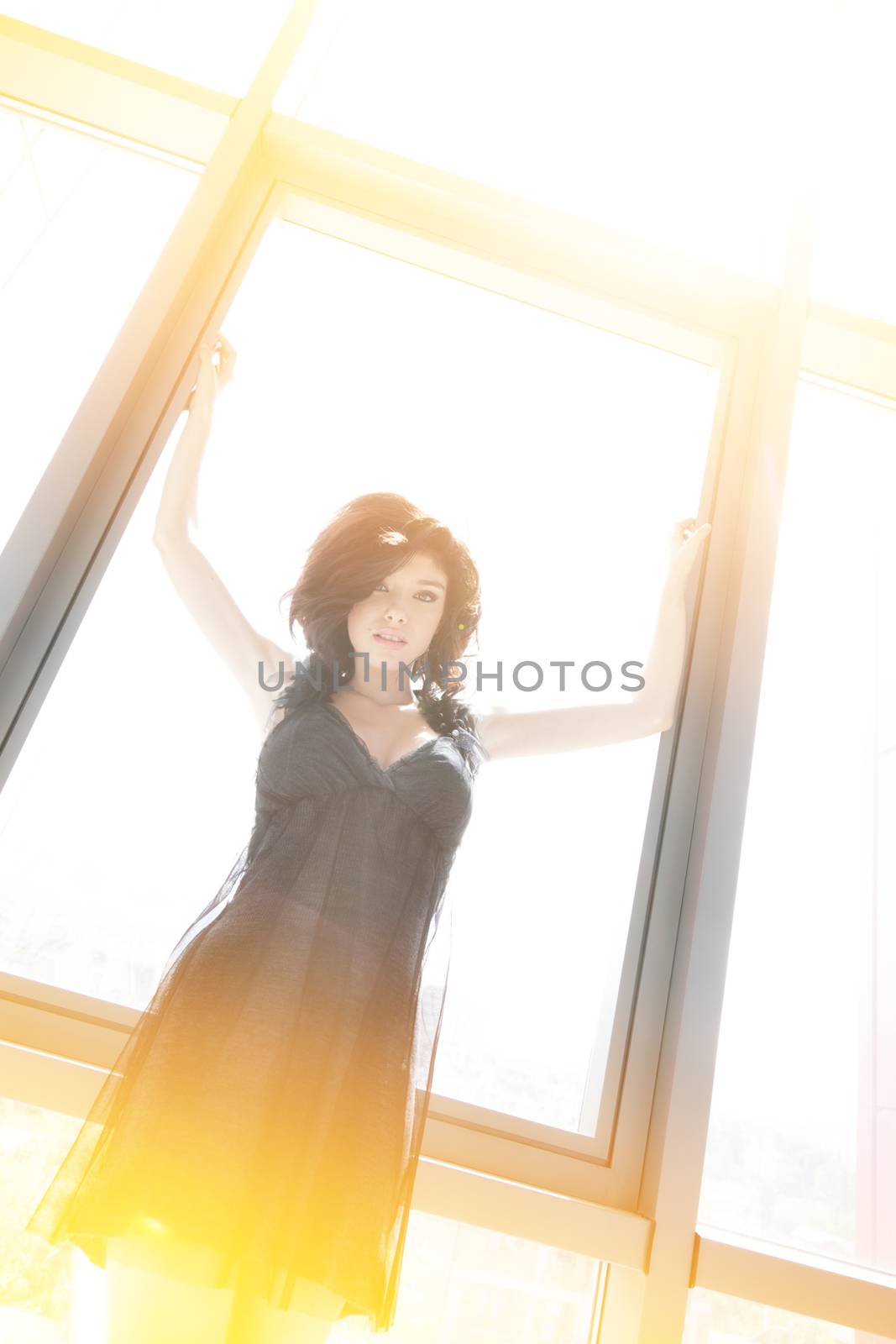 Young beautiful woman is stretching her arms on the window