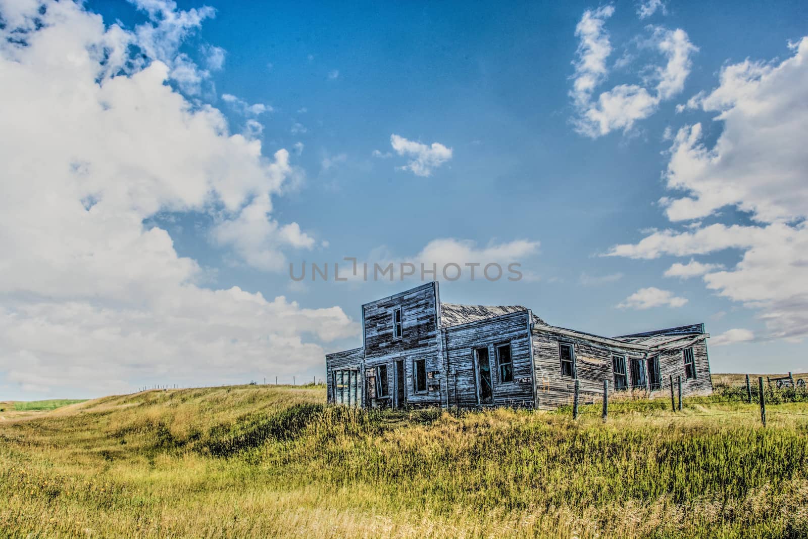 Abandoned building in fallow field under cloud studded blue skies
