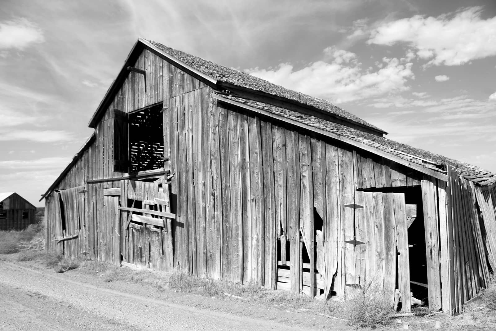 Weathered barn in the Panhandle region of Idaho in black and white with puffy clouds