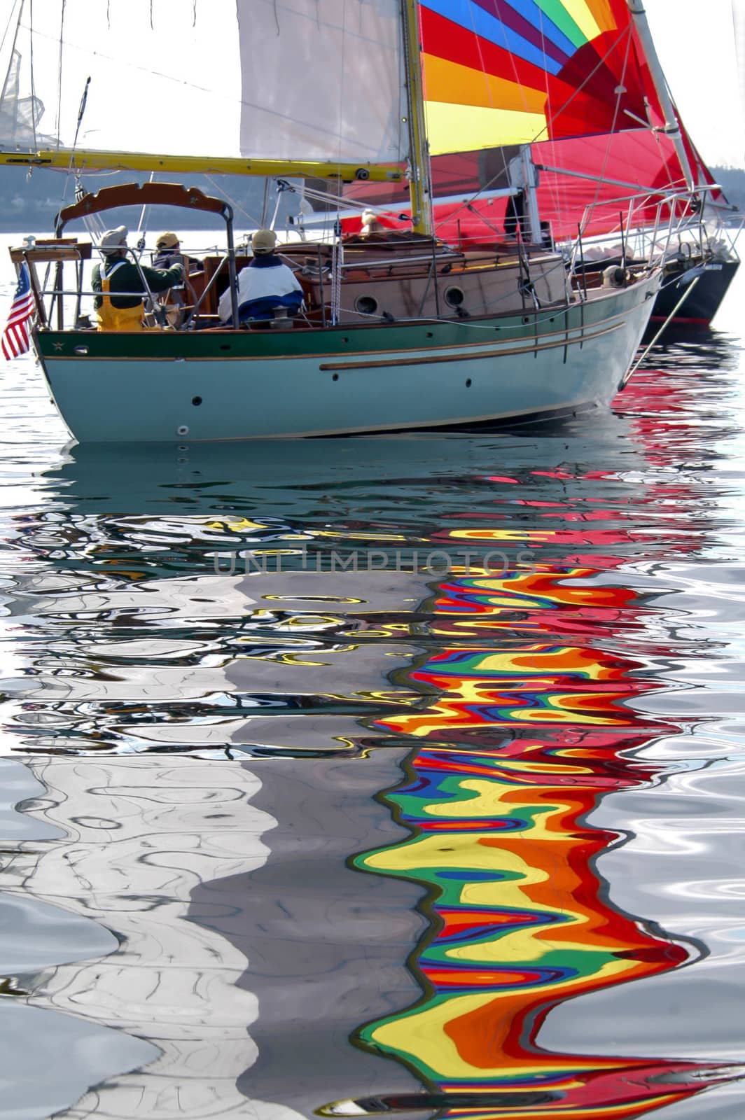 Reflections of colorful sails on calm day.