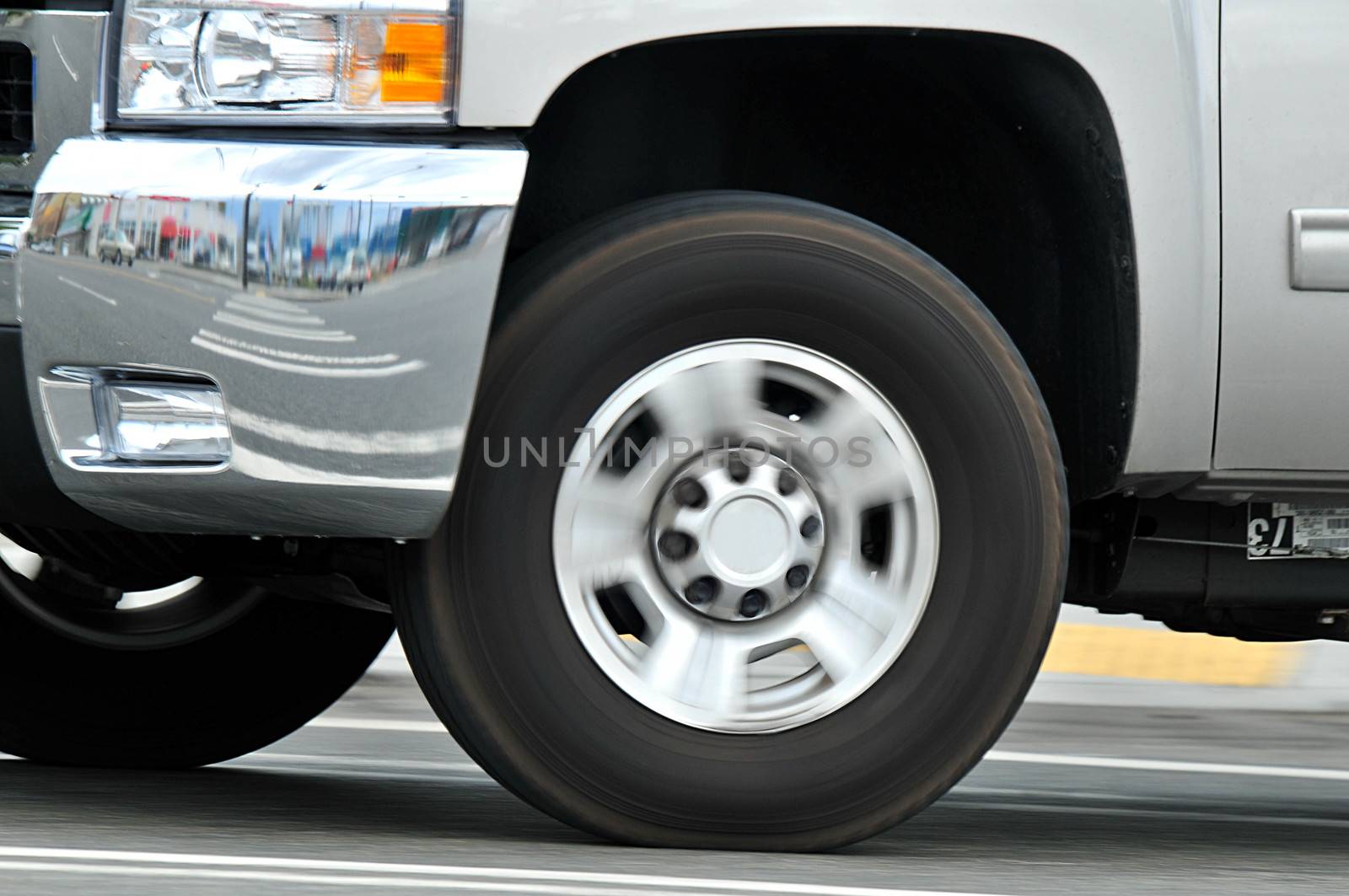 Wheel of automobile in motion.  Car moving, but in focus, street and whell blurred