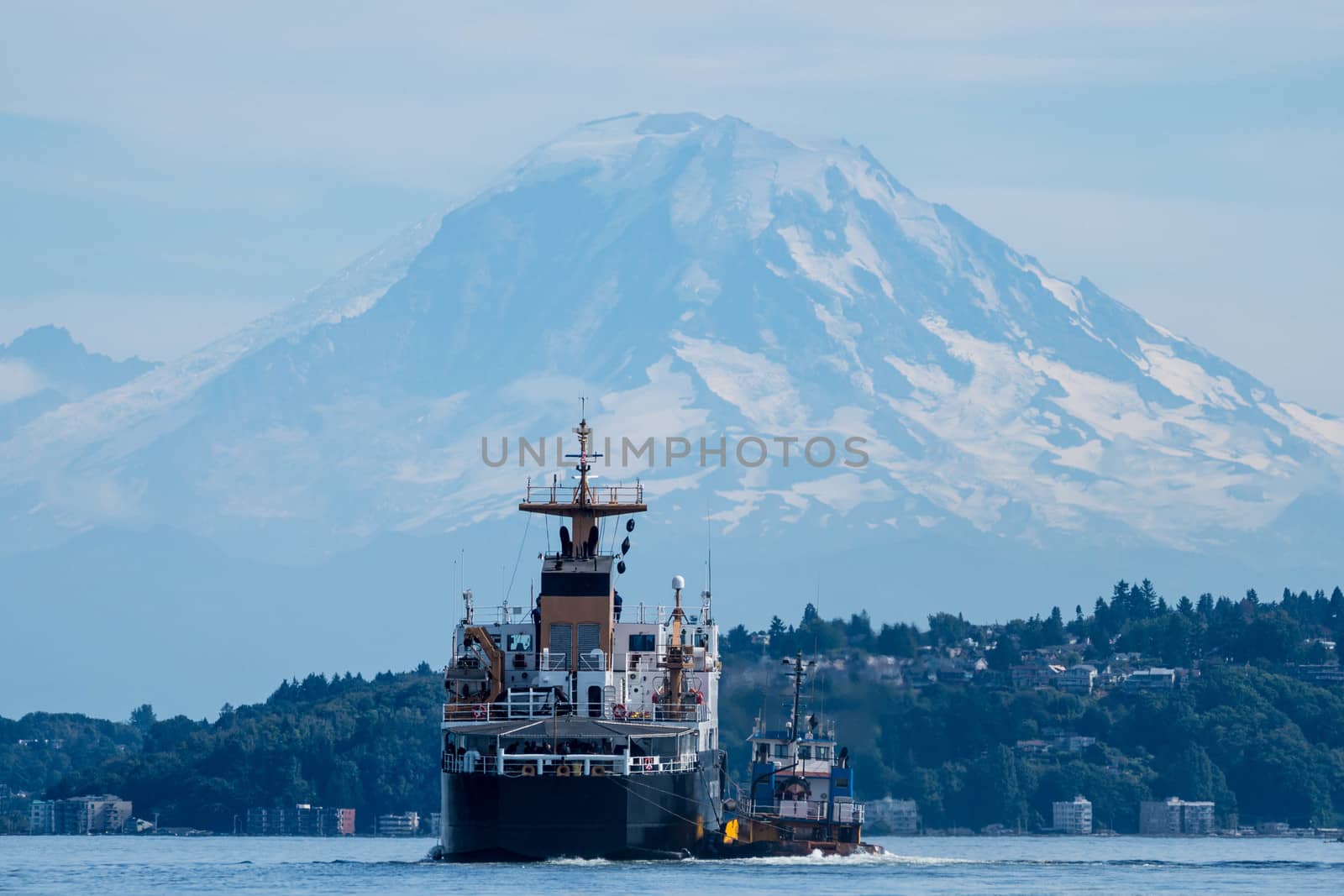 Small tug rigged to the side of a US Coast Guard vessel on Seattle's Elliott Bay