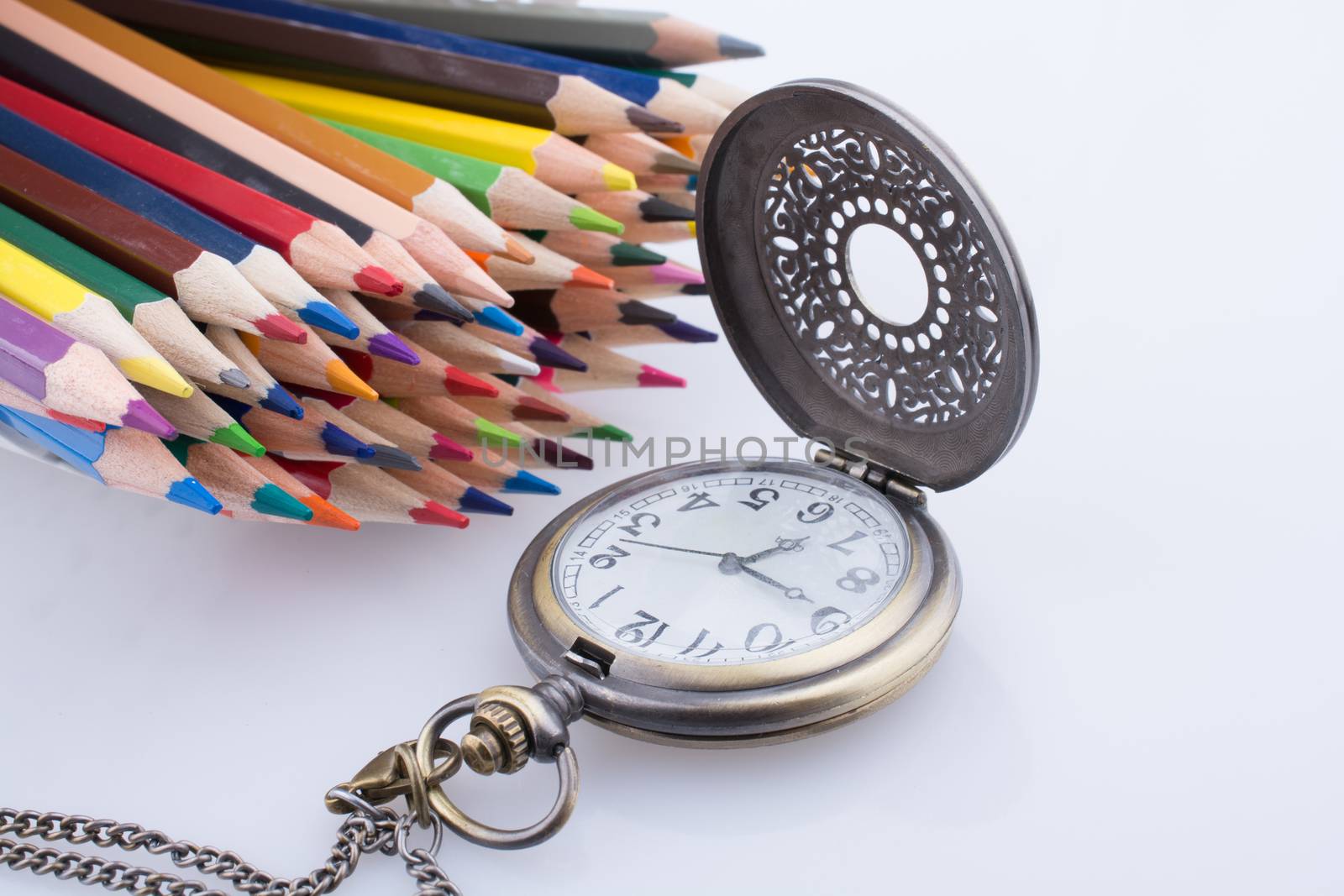 Retro style classic pocket watch and color pencils on white background