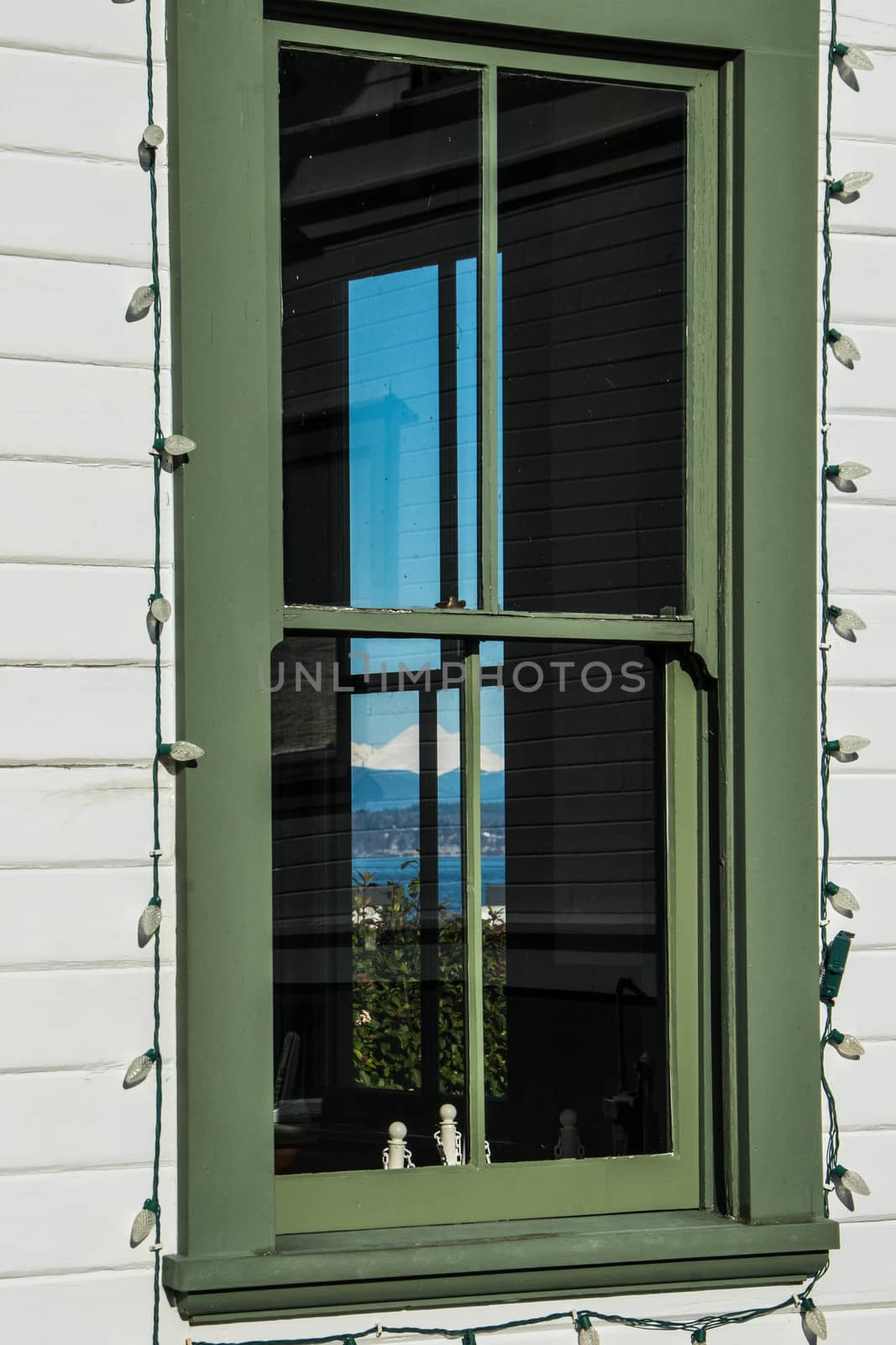 Windows in lighthouse keeper's shed showing clear blue sky and Mukilteo Lighthouse reflected