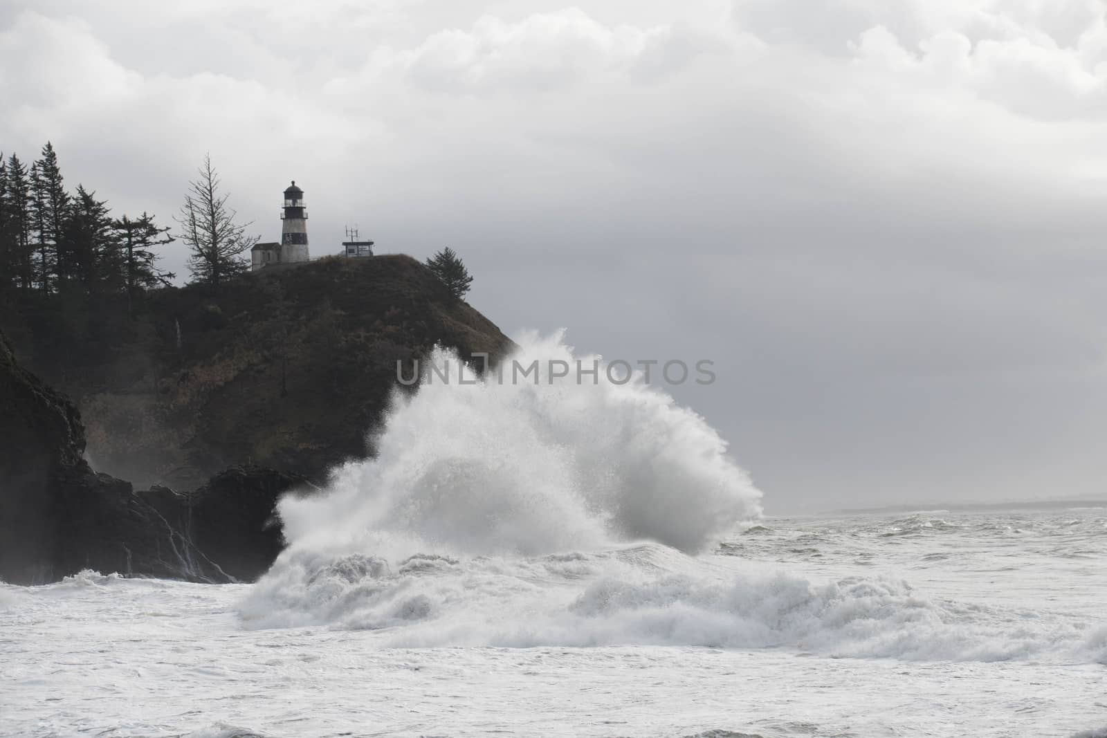 Cape Disappointment Lighthouse with Pacific Ocean swells breaking at the foot of the cliff