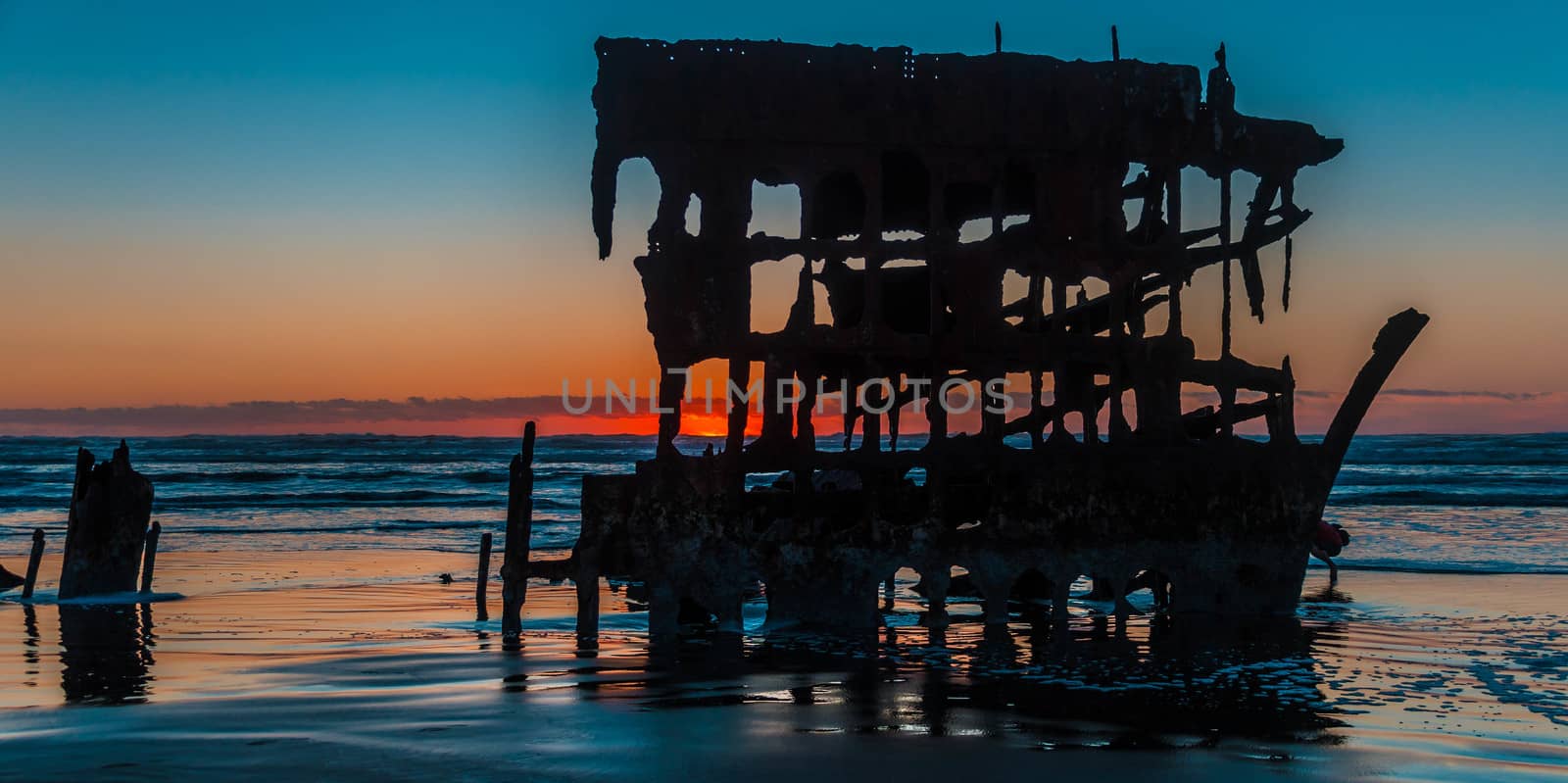 Sun setting behind the wreck of the Peter Iredale on the beach in Fort Stephens State Park, Oregon