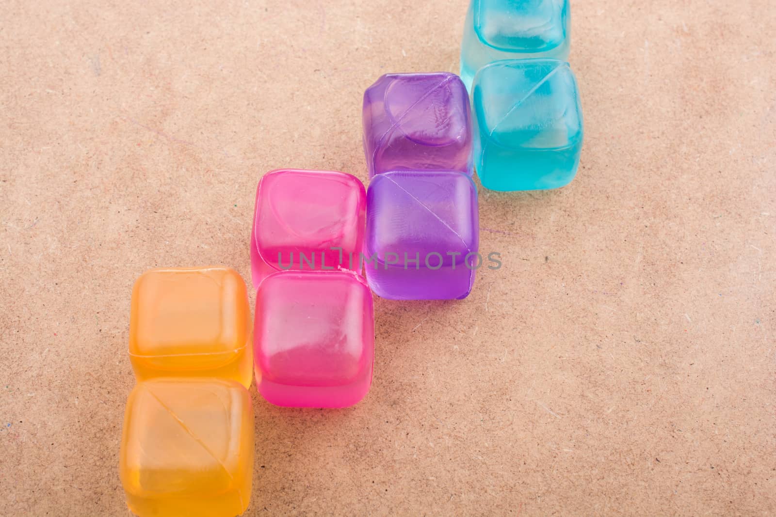 Fake colorful ice cubes on a brown background