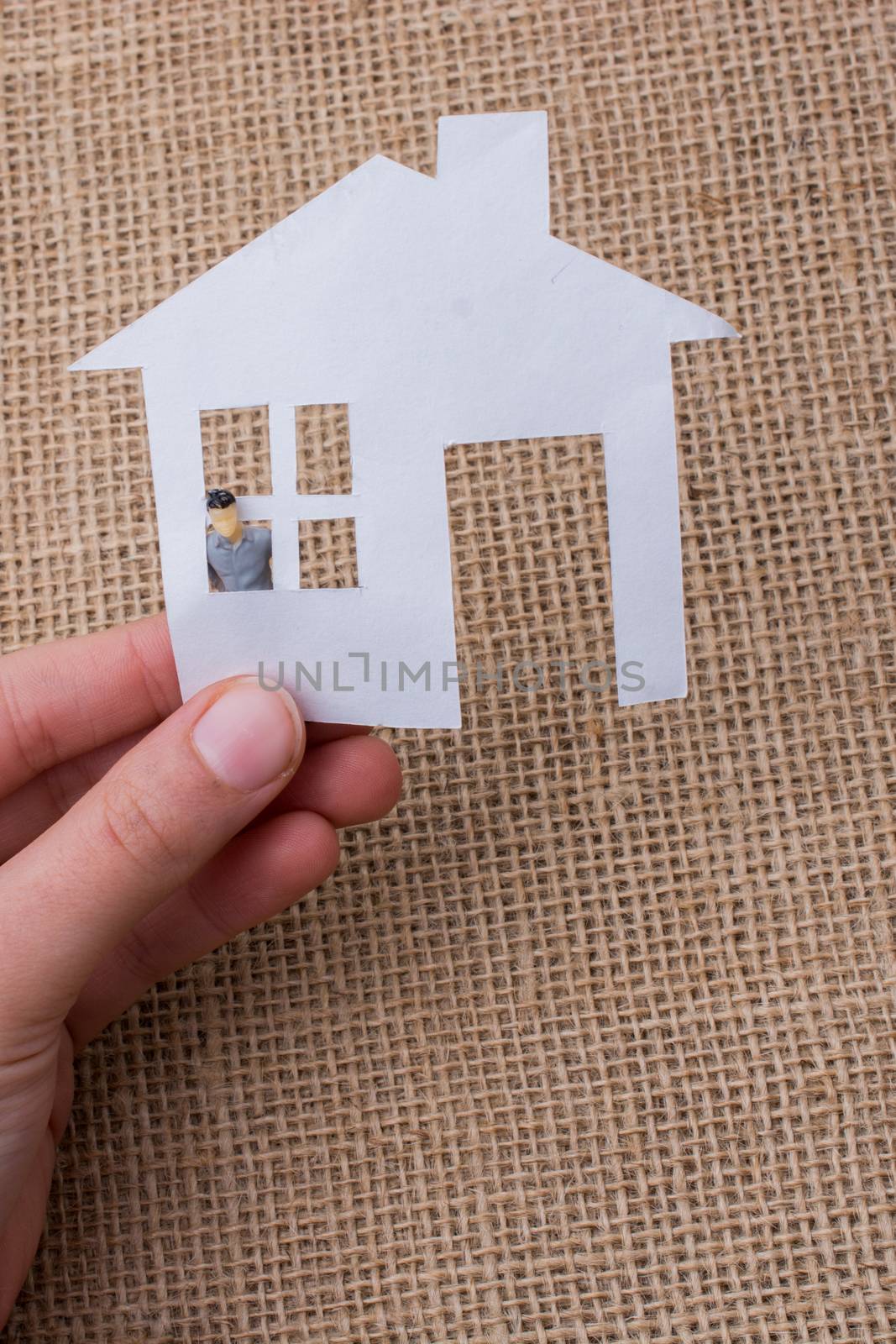 Paper house and a man figurine on a linen canvas background