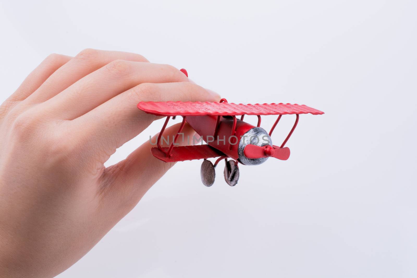 Hand holding a red toy plane on a white background