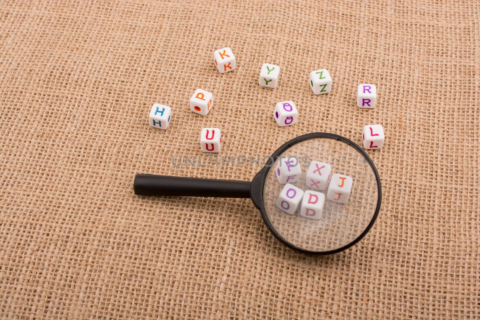 Colorful alphabet letter cubes behind a magnifying glass