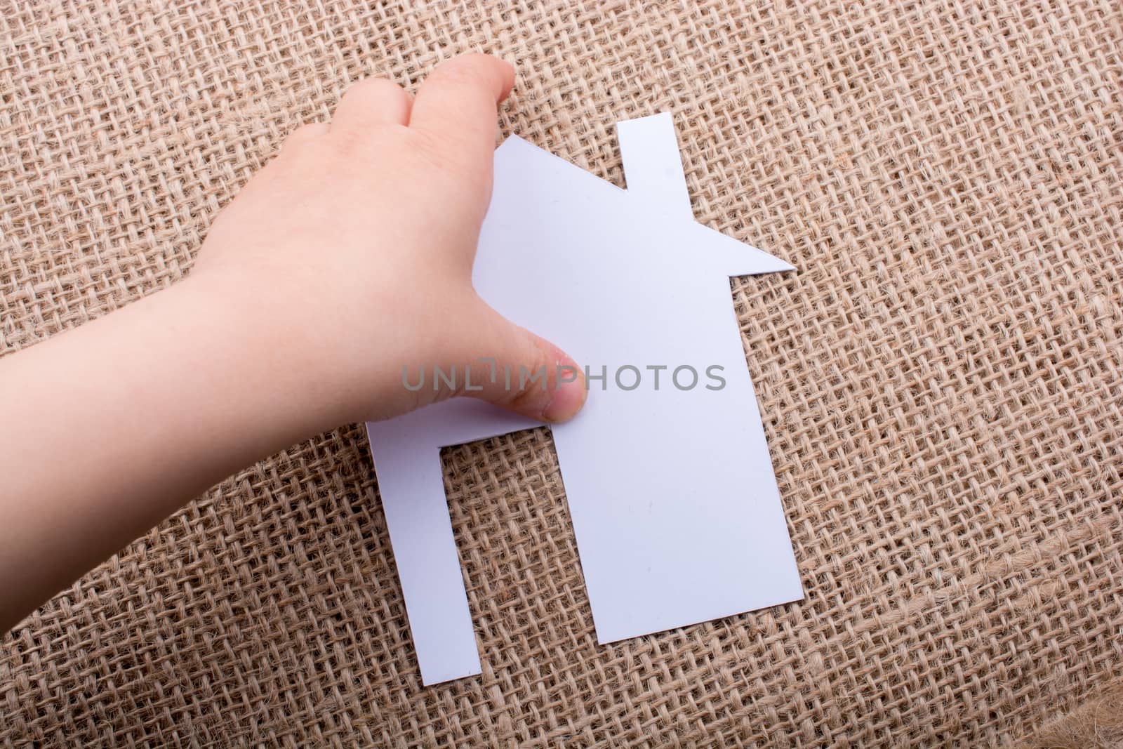 Hand holding a aper house on a canvas background