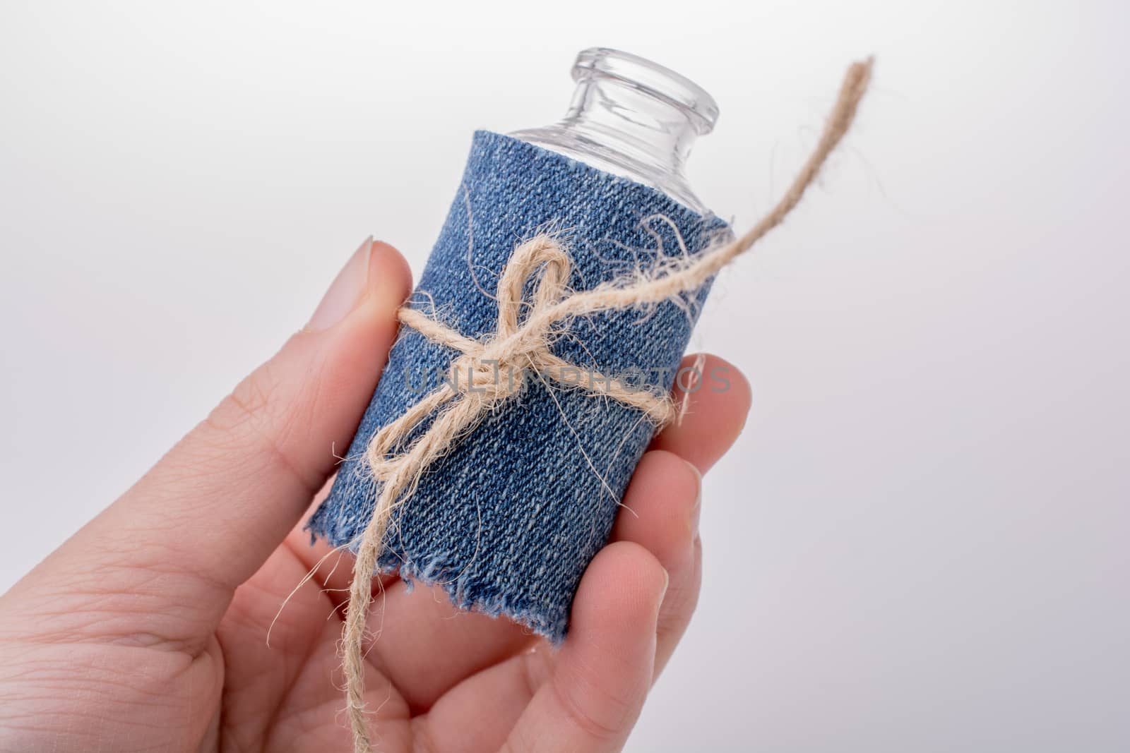 Little empty bottle covered with denim canvas in hand