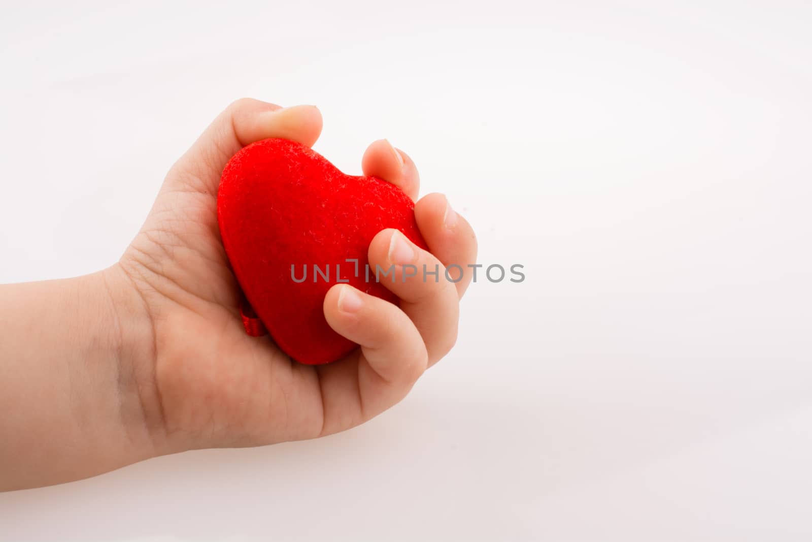 Little red color heart shape in hand on white background