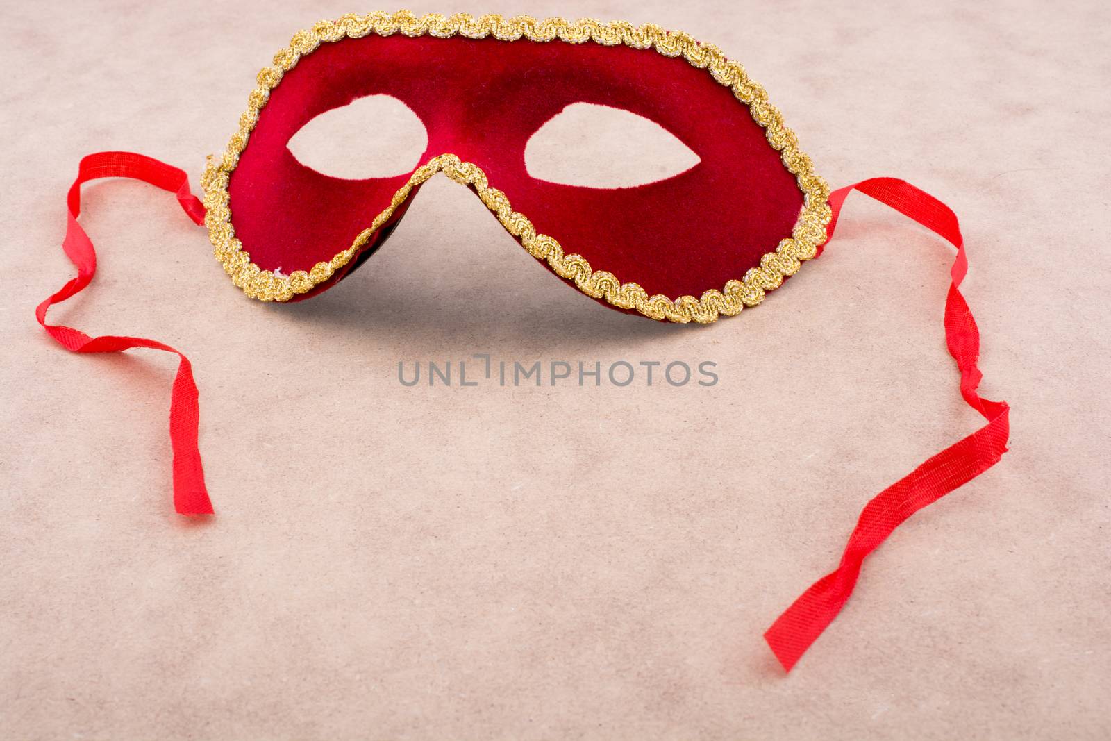 Beautiful festive carnival mask with ribbons on light brown background
