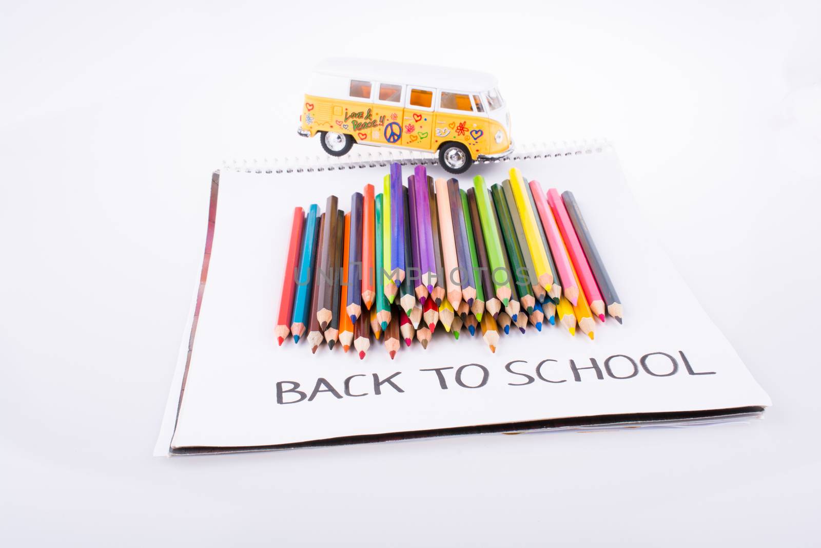Color pencils, van and back to school title on a notebook