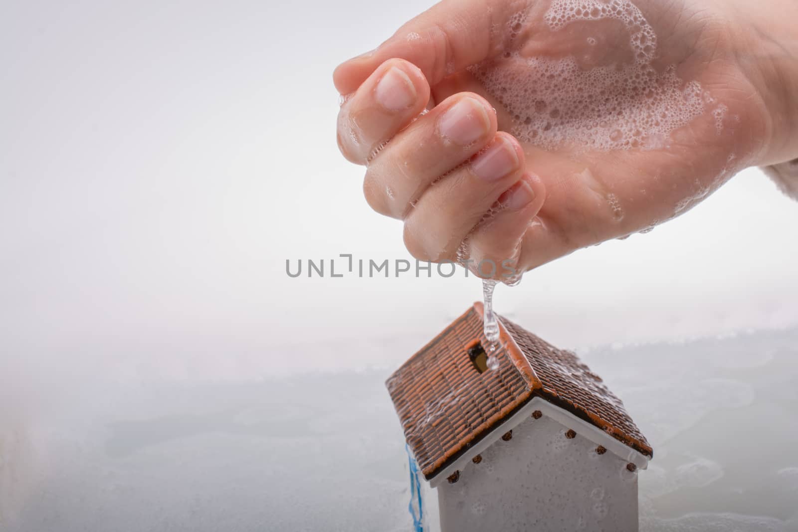 Hand holding a model house in foamy water