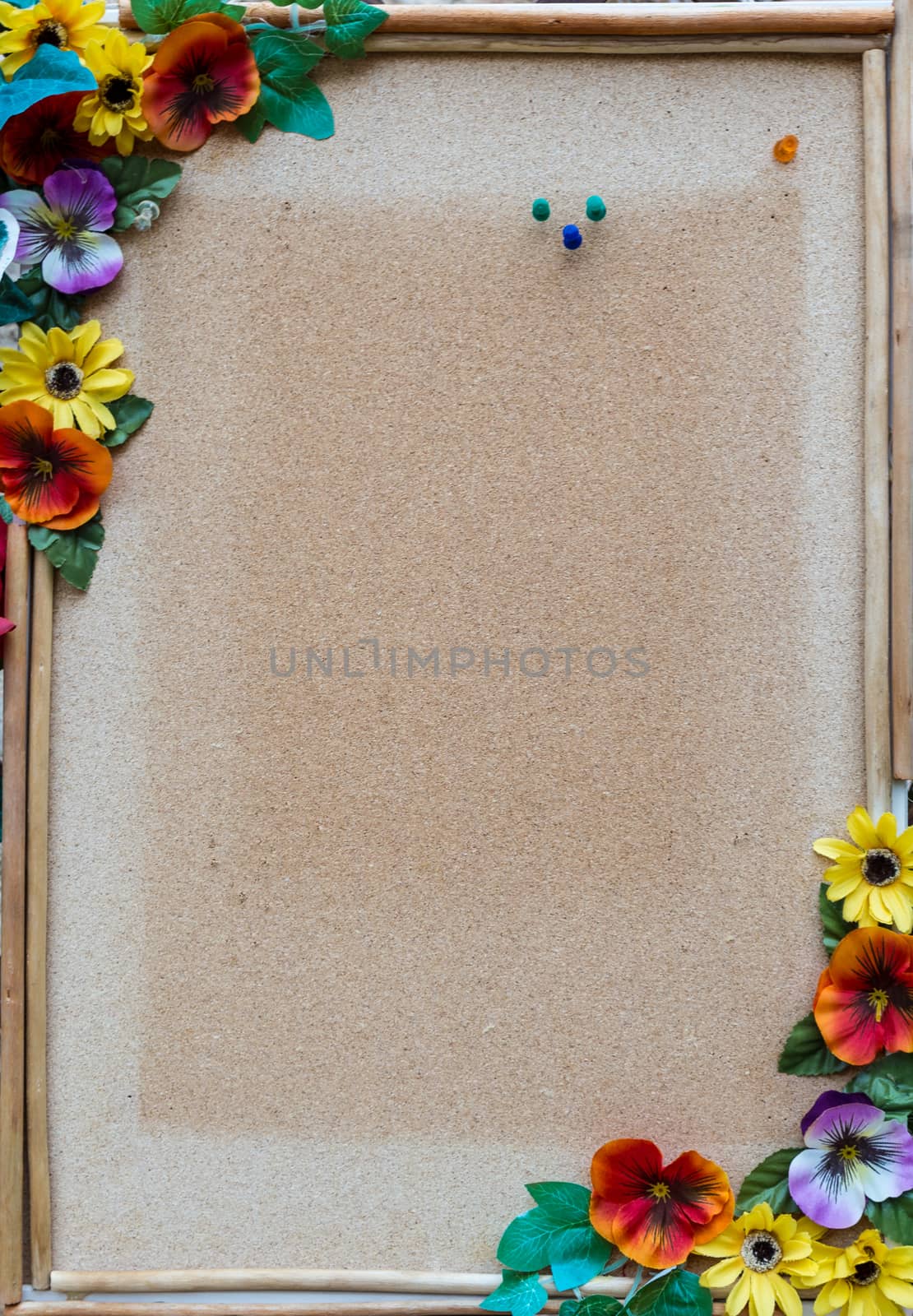 empty cork board with wooden frame and colorful flowers on the edges