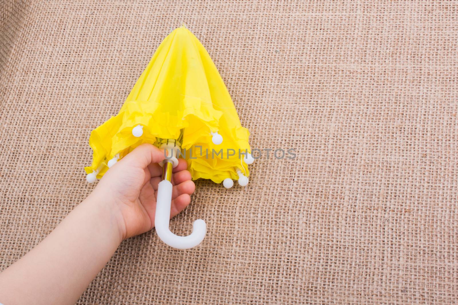 Yellow umbrella in a toddlers hand on canvas