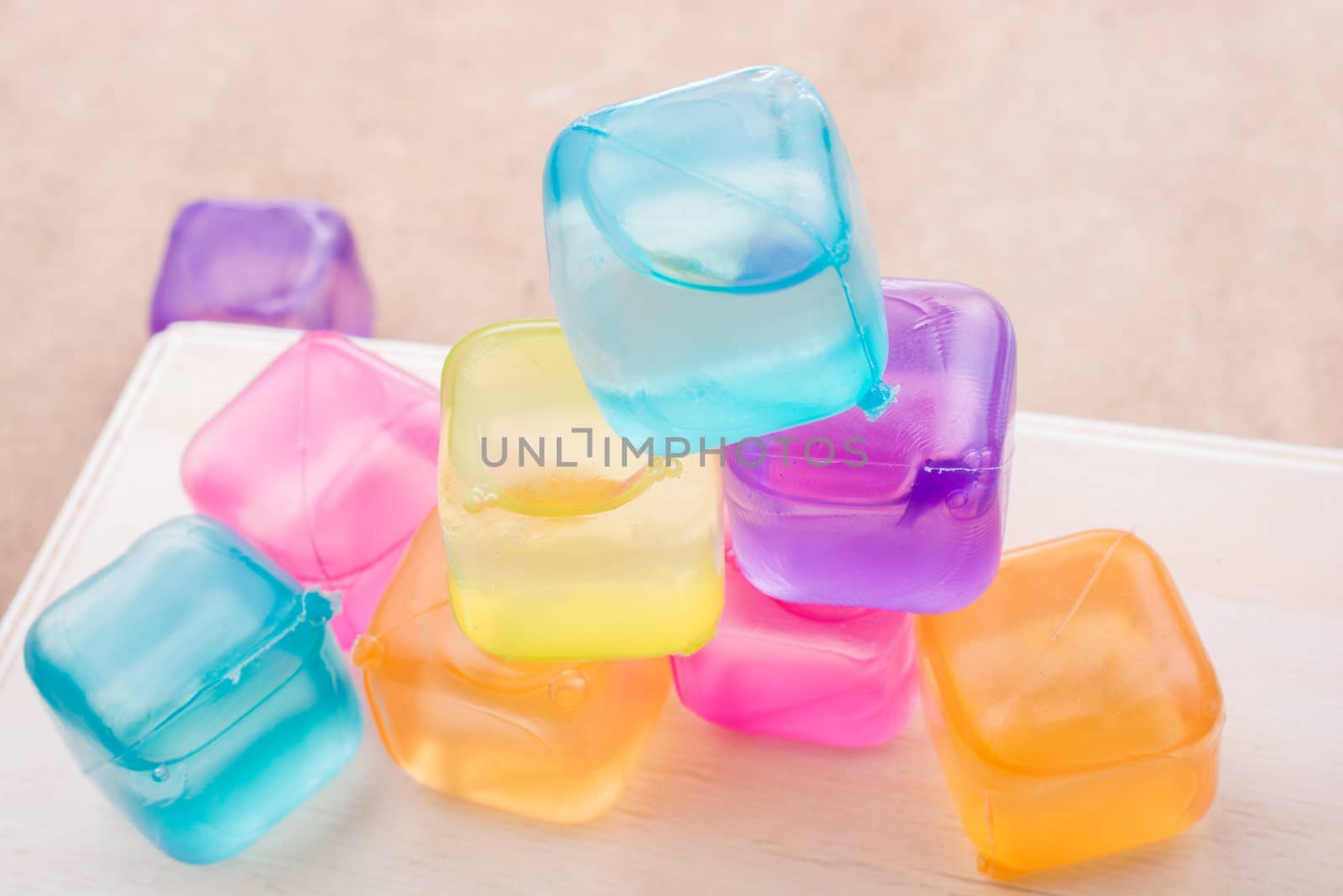 Fake colorful ice cubes on a brown background