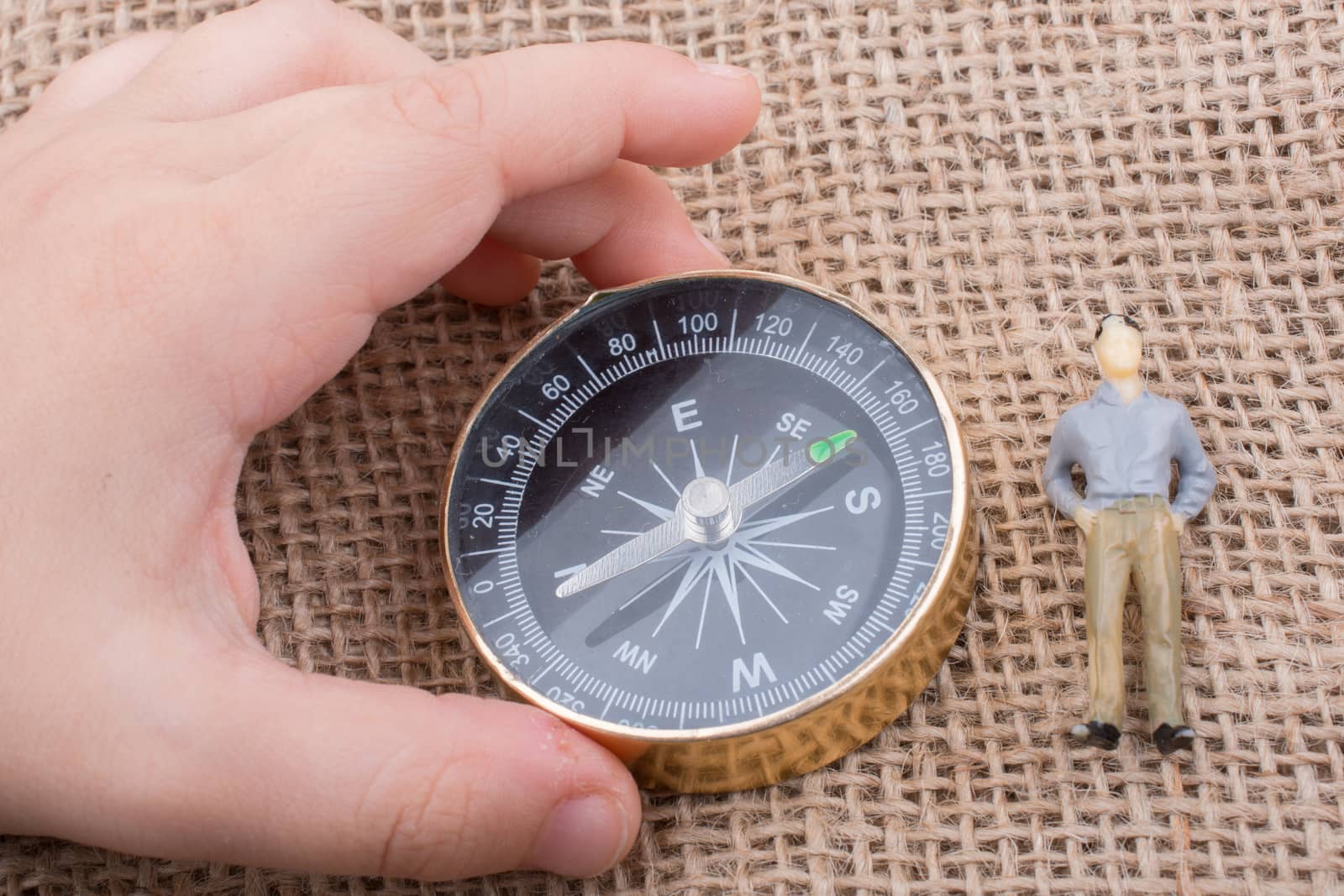 Hand holding a compass beside a  figurine