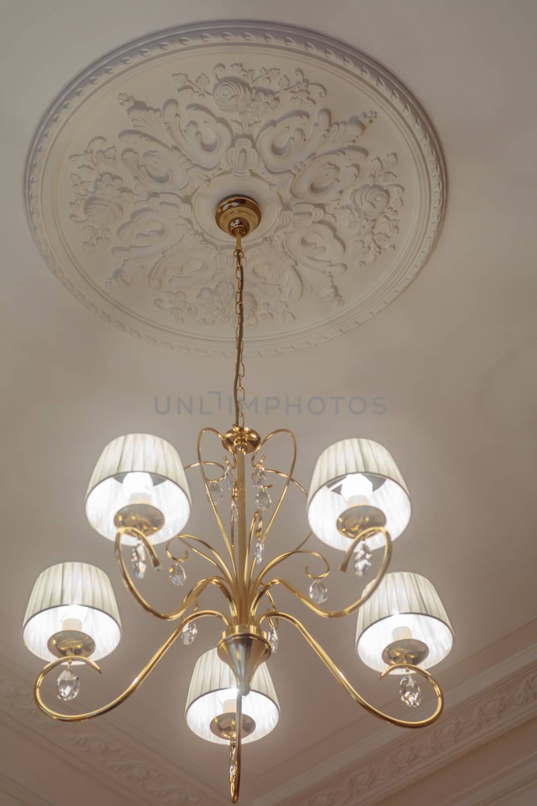 Huge chandelier closeup with electric bulbs on fancy ceiling