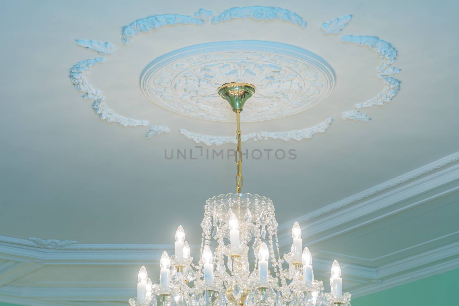 Huge chandelier closeup with electric bulbs on fancy ceiling