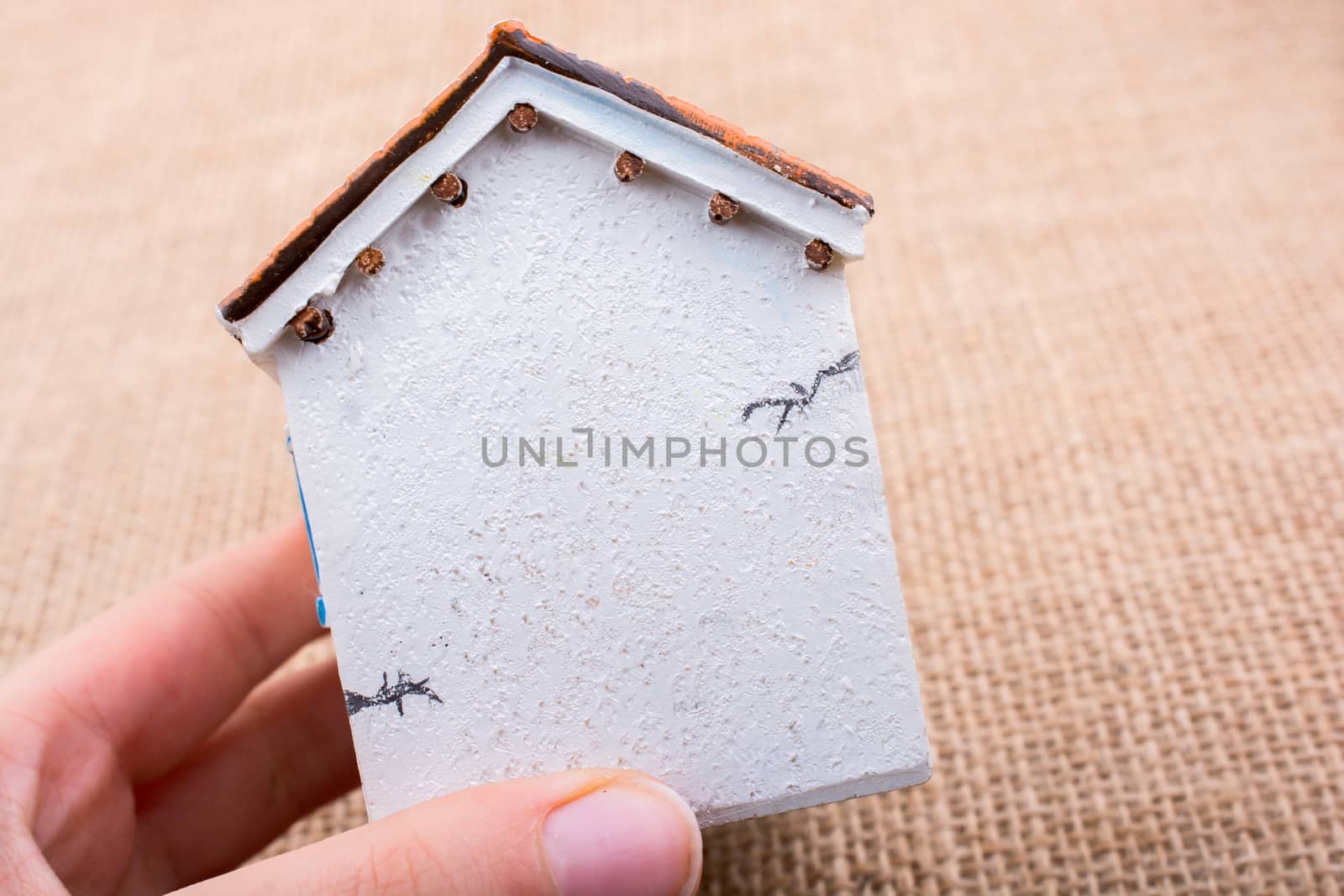 Little model house and  a hand  on a light  brown color background