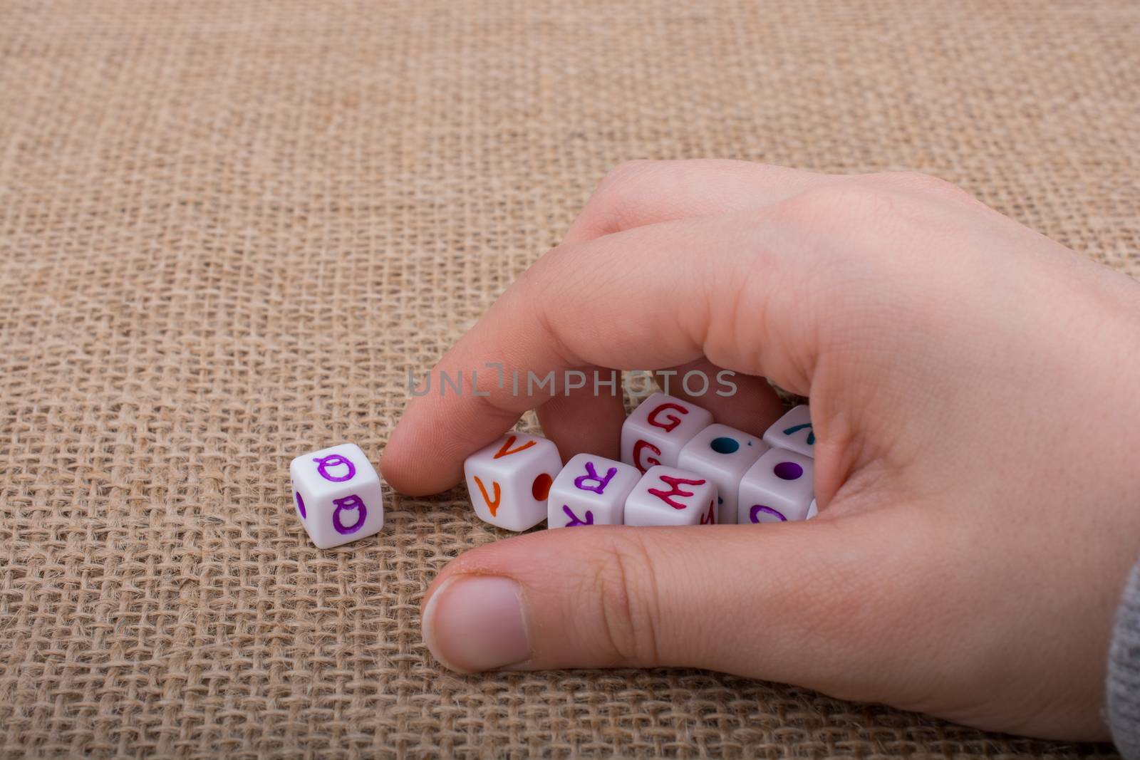 Colorful alphabet letter cubes in handon a  canvas background