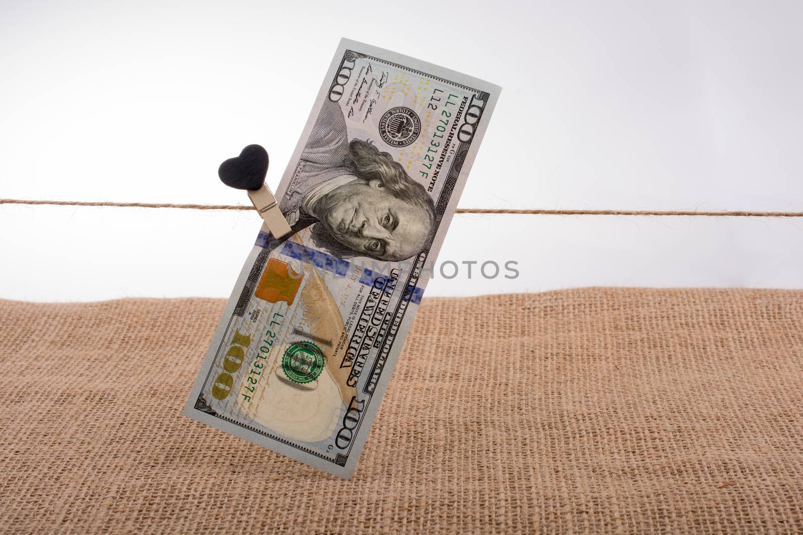 American 100 dollar banknotes with a heart clip on a string