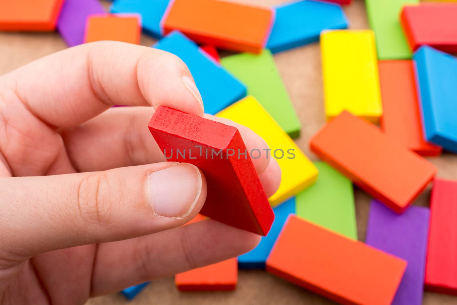 Hand holding one of the wooden blocks of various colors