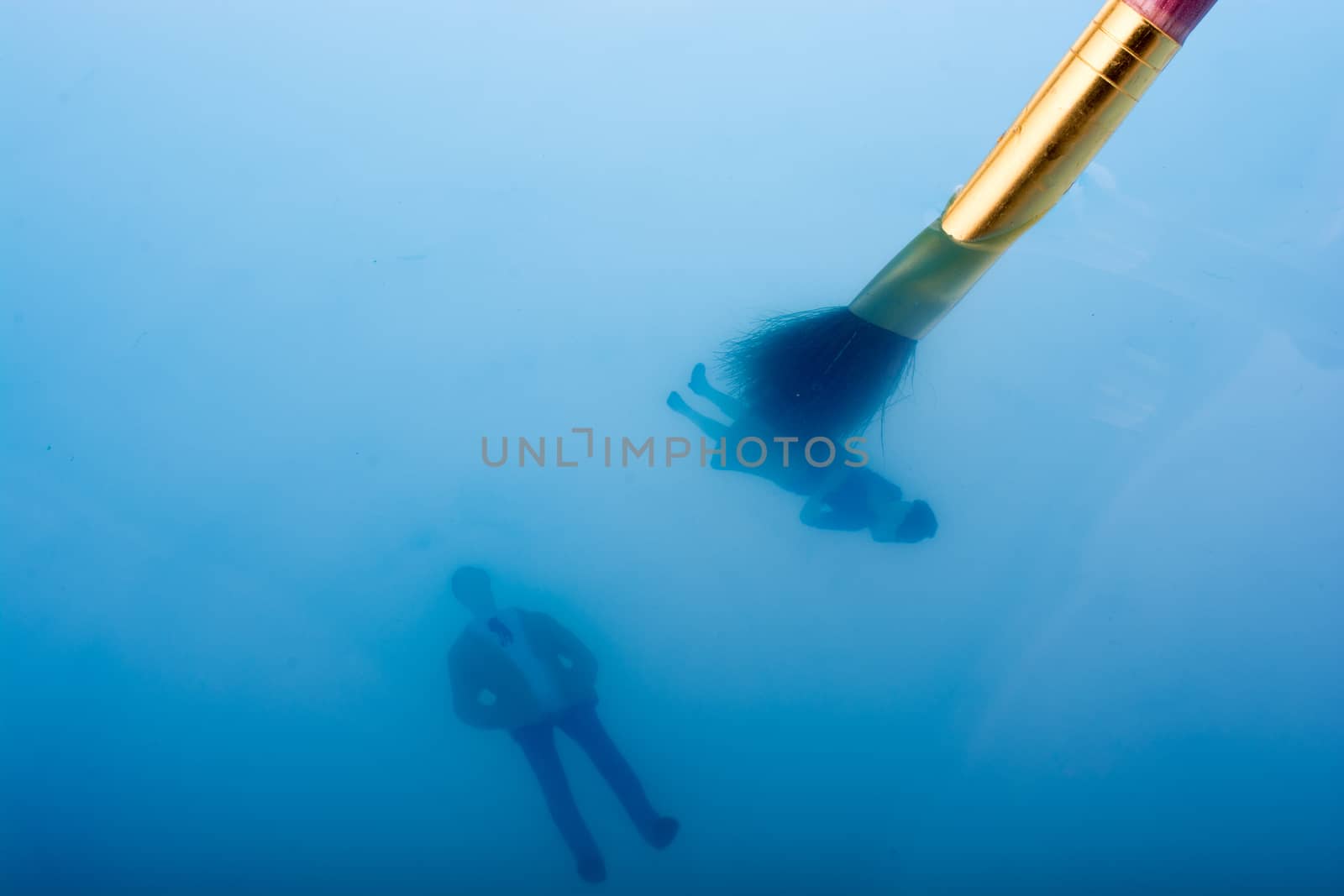 Painting brush and little floating figurines in blue water
