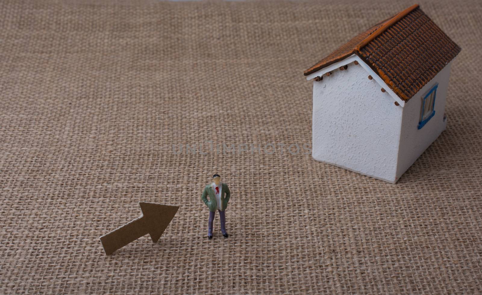 Model house and an arrow beside a man figure on a canvas