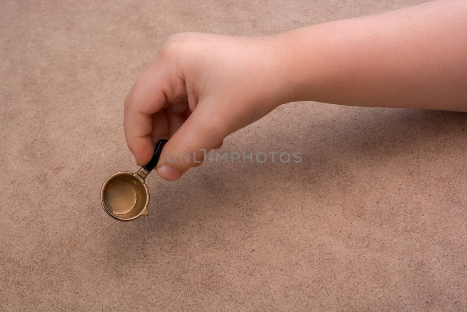 Hand holding a little model pan as a kitchen utensil