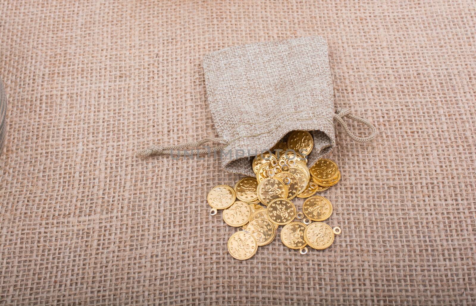 Fake gold coins out of a little sack on canvas