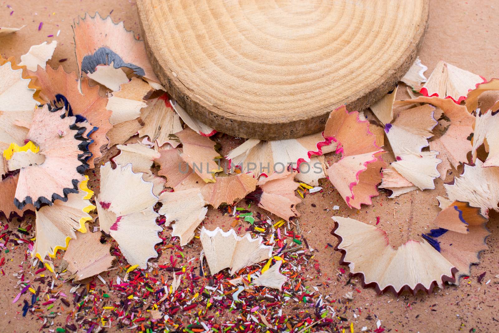 Colorful pencil shavings and a piece of wood