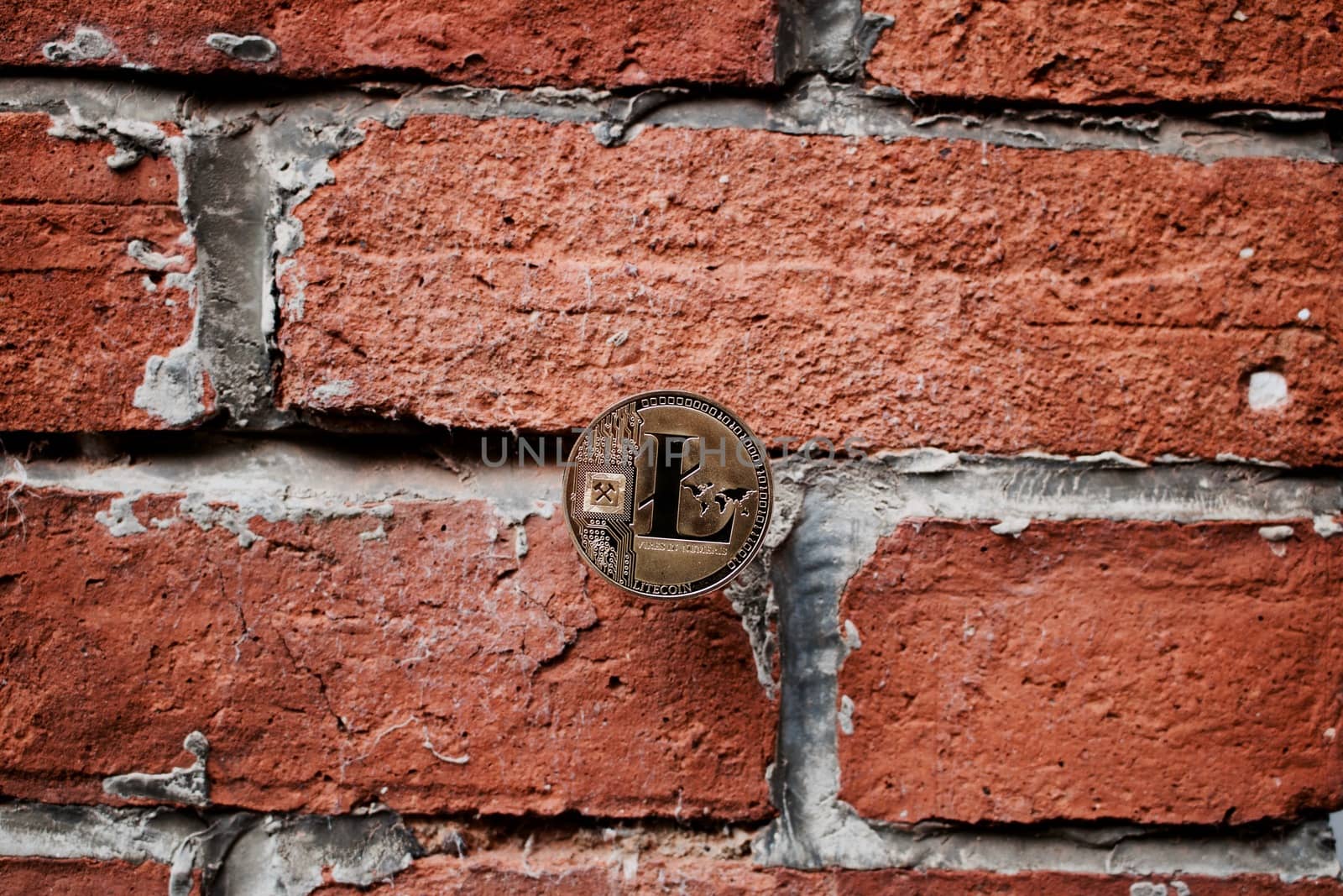 Digital currency physical gold litecoin coin on the brick wall.