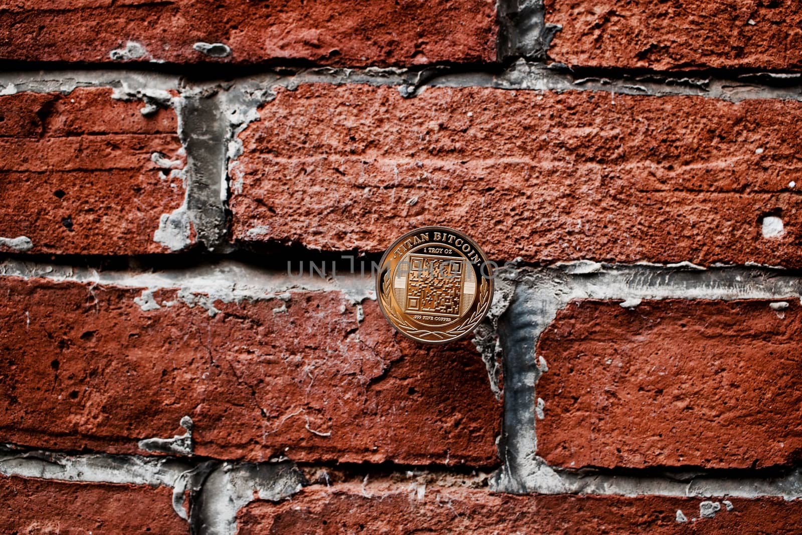 Digital currency physical gold titan bitcoin coin on the brick wall.