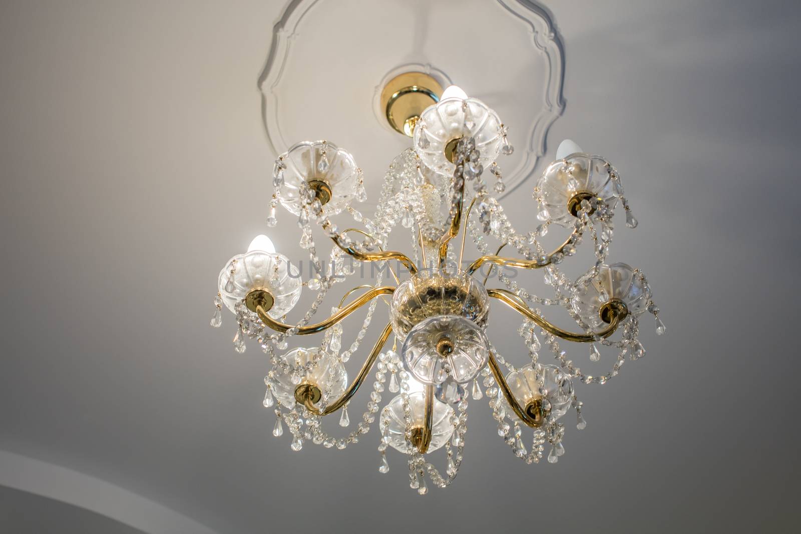 Huge chandelier closeup with electric bulbs on fancy ceiling